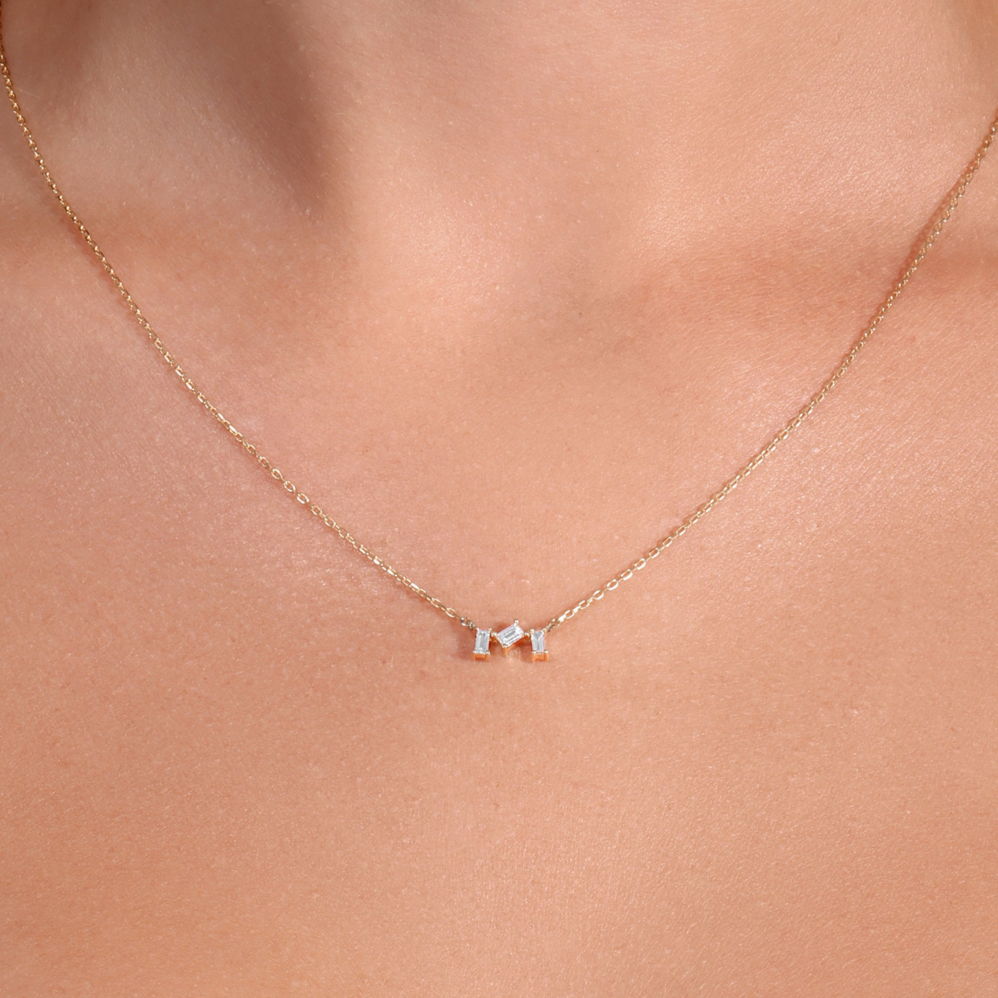 Necklace with small pendants on a person wearing a white top