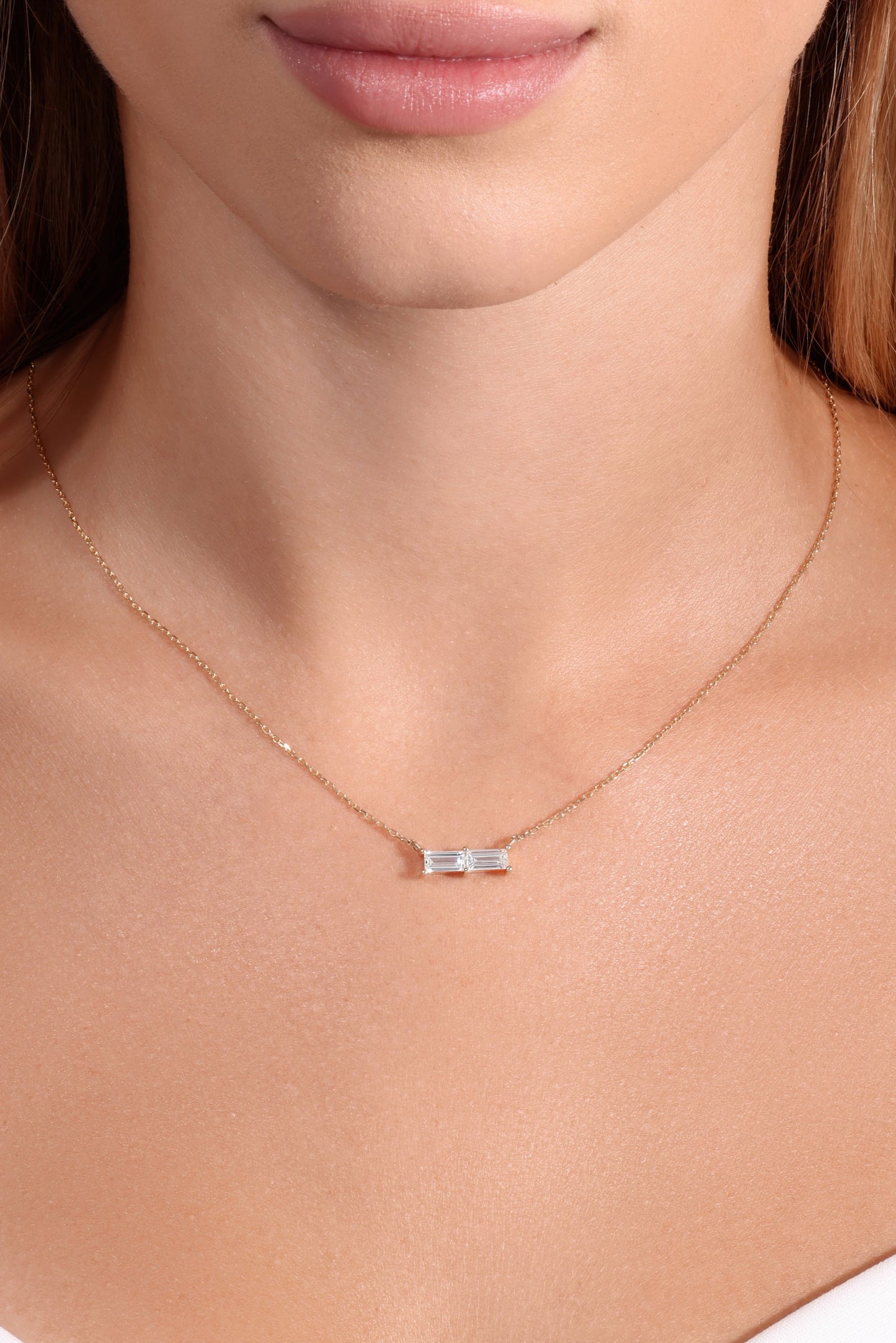 Necklace with a small pendant worn by a person in a white top