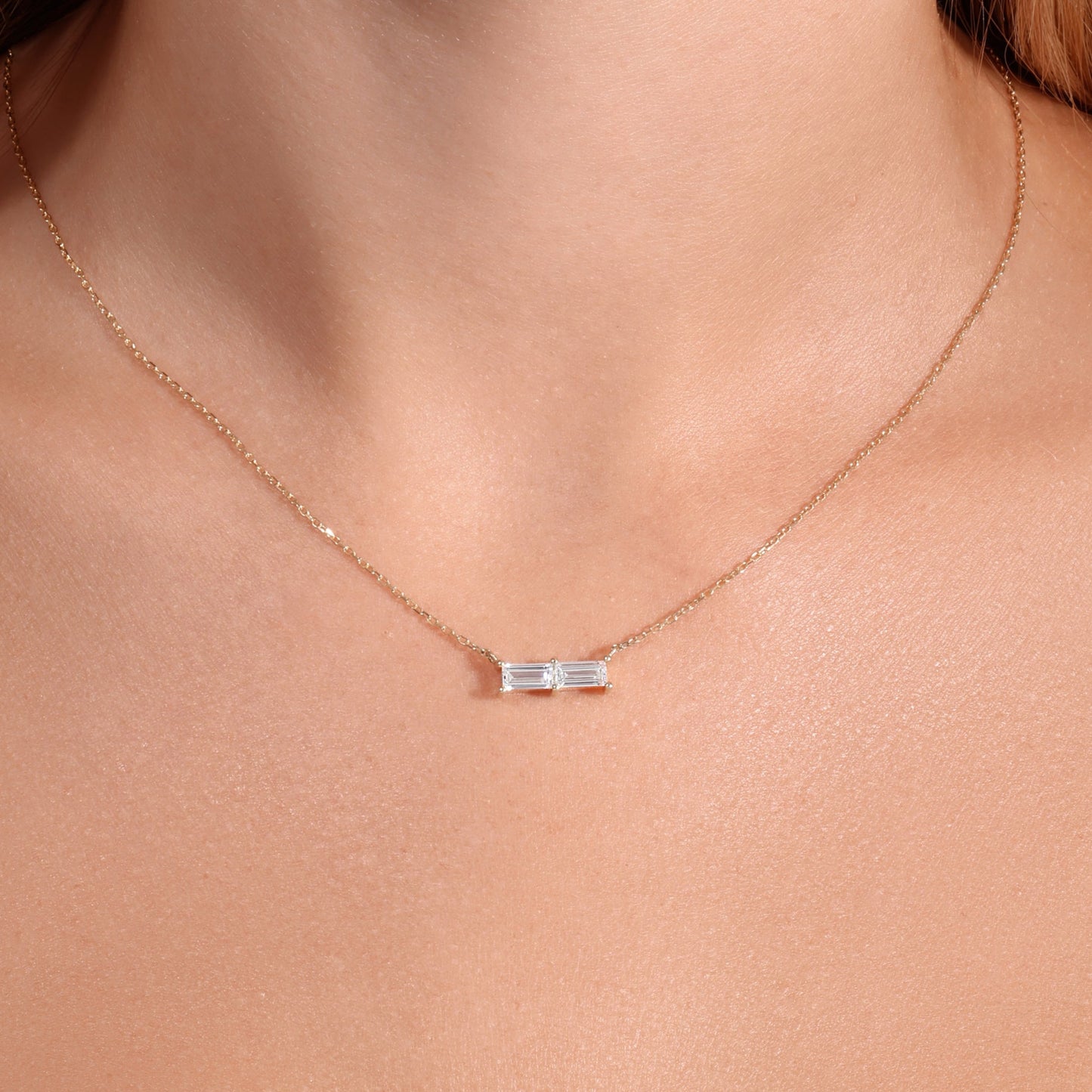 Necklace with a small pendant worn by a person in a white top