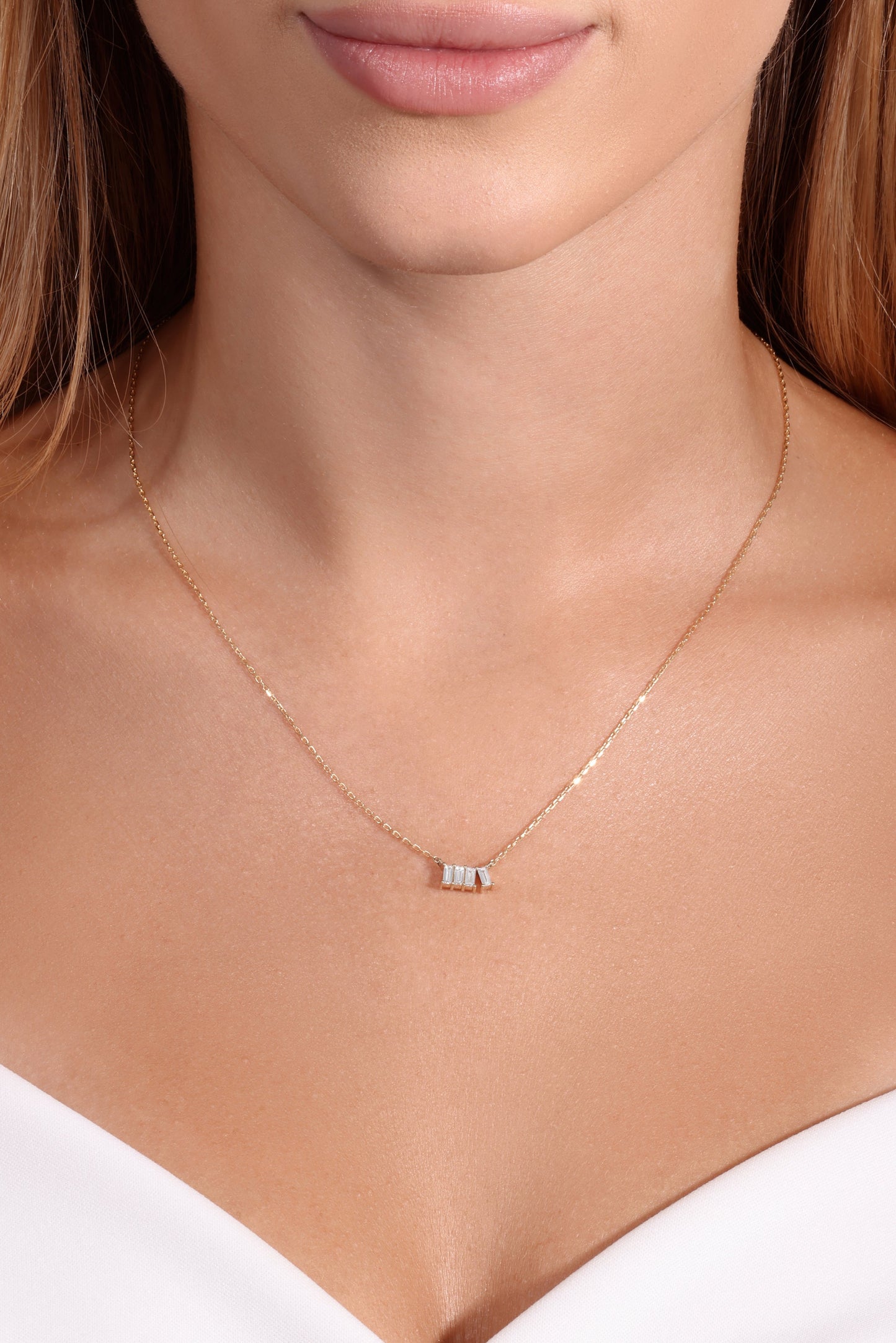 Necklace with a small pendant worn by a person in a white top