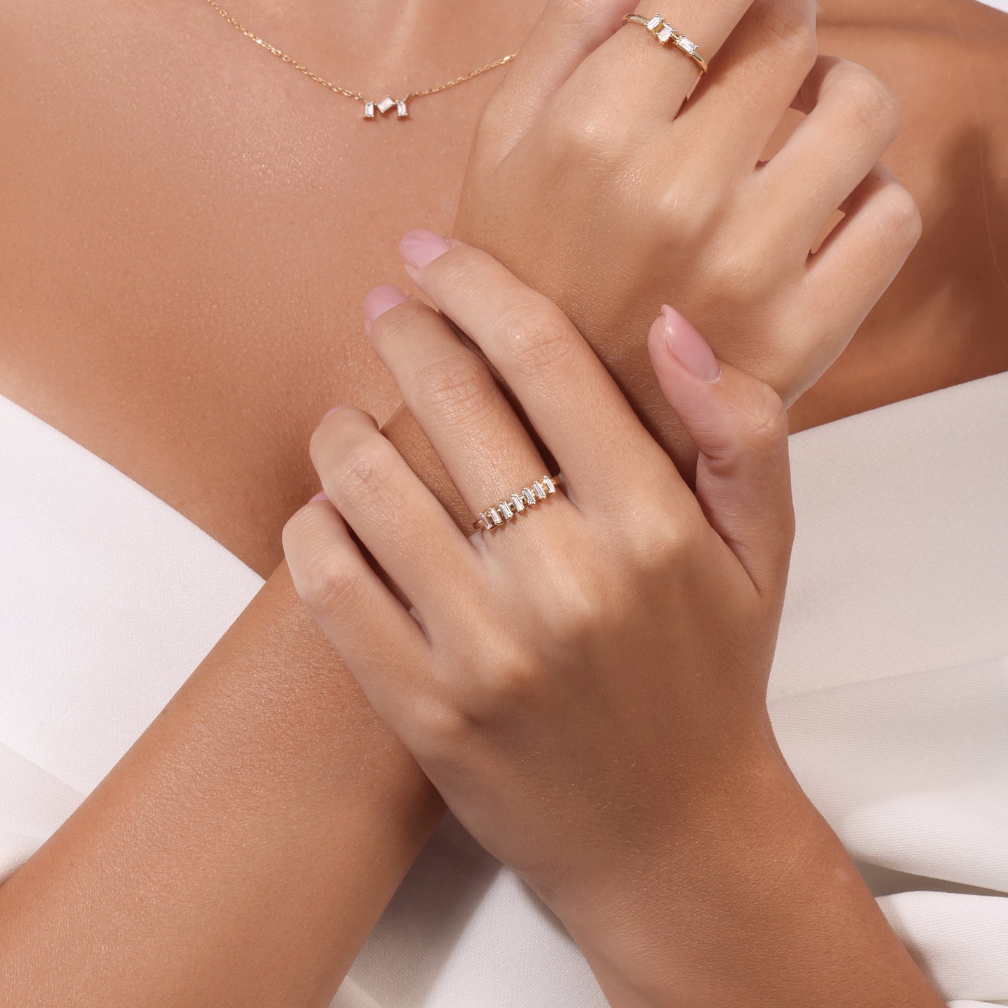 Delicate gold necklace with three baguette diamonds, gold ring with three baguette diamonds, and gold ring with seven baguette diamonds