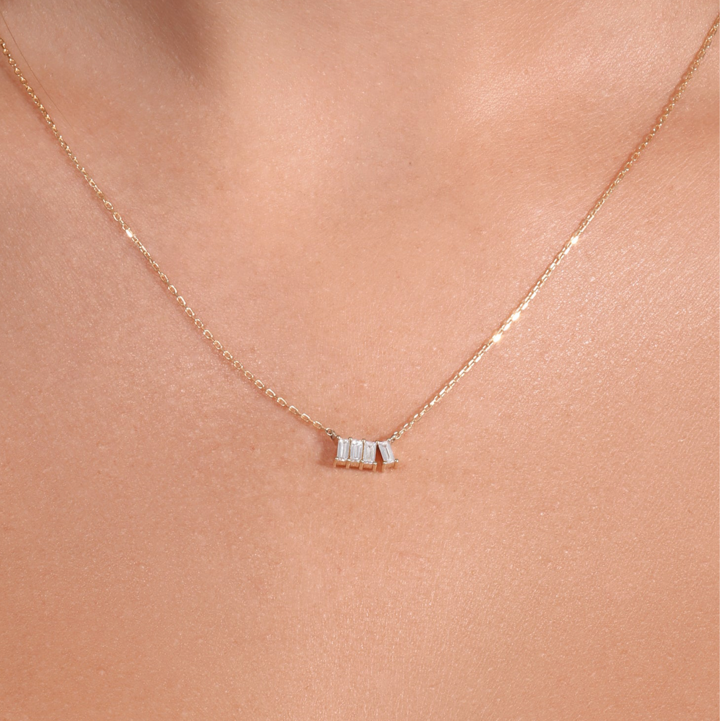 Gold necklace with a small pendant on a person's neck