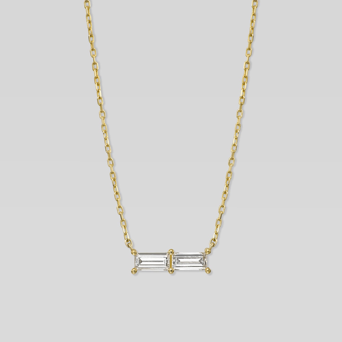 Gold necklace with a rectangular diamond pendant on a light gray background