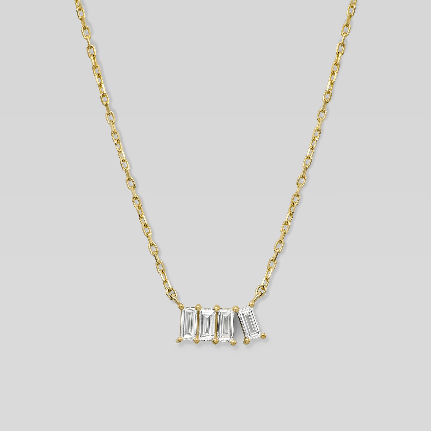 Gold necklace with four baguette-cut diamonds on a light gray background