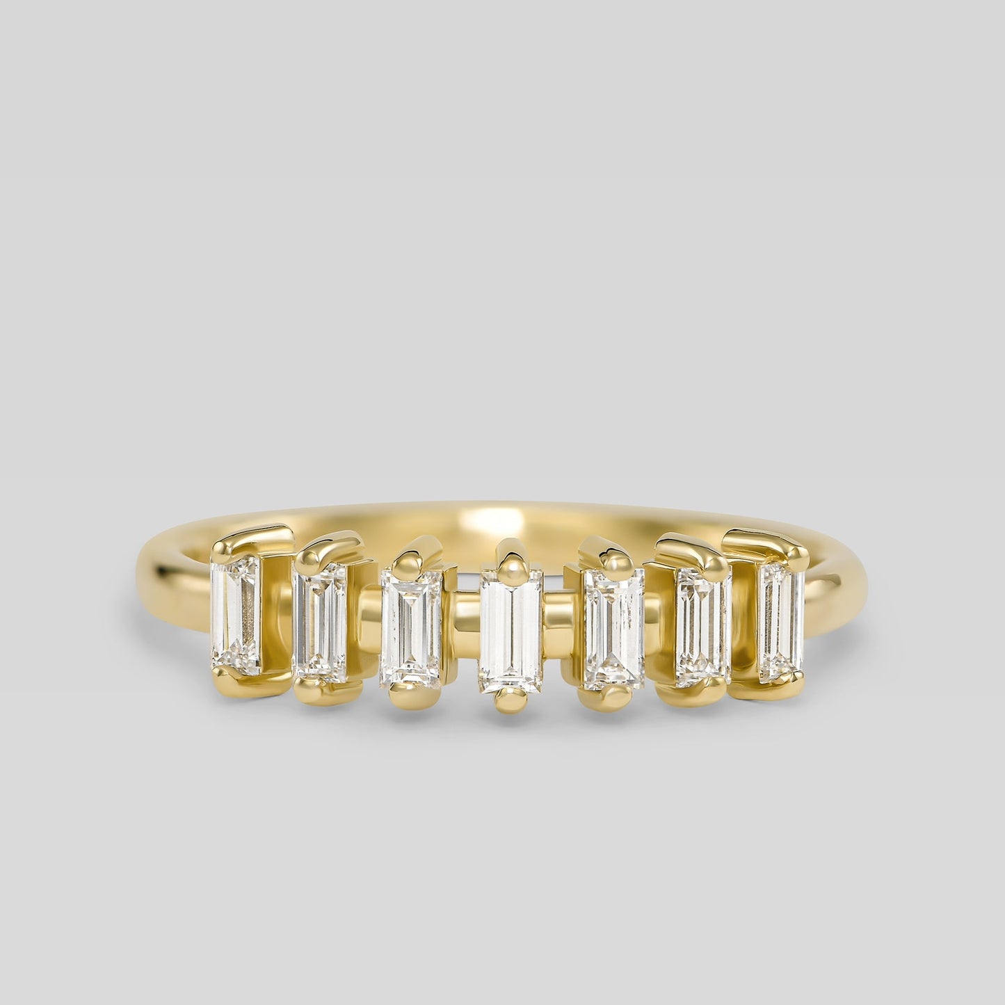 Gold ring with baguette-cut diamonds on a light gray background