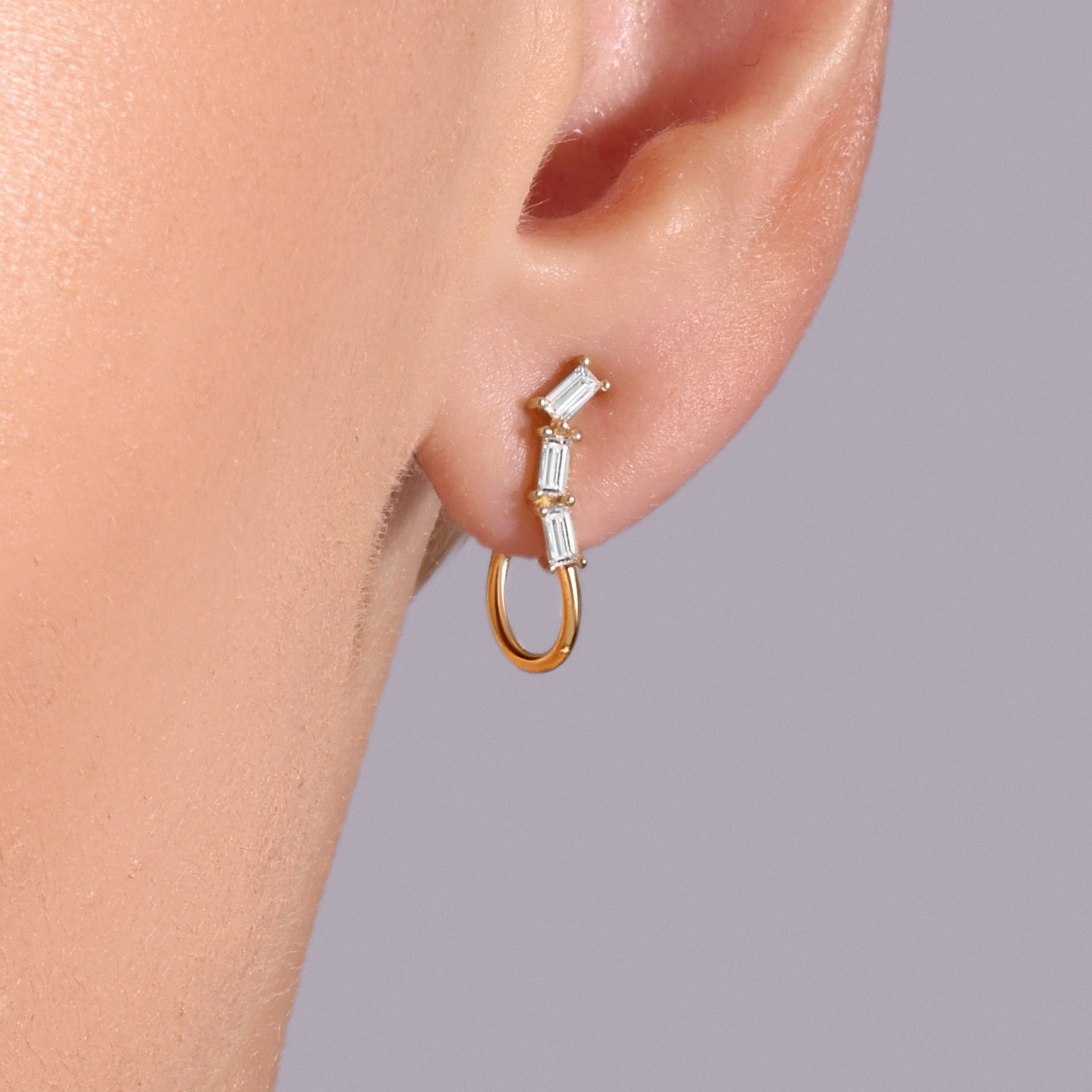 Close-up of model wearing Levi Tzeiger Jewelry gold hoop earrings with baguette diamond details, minimalist and elegant style