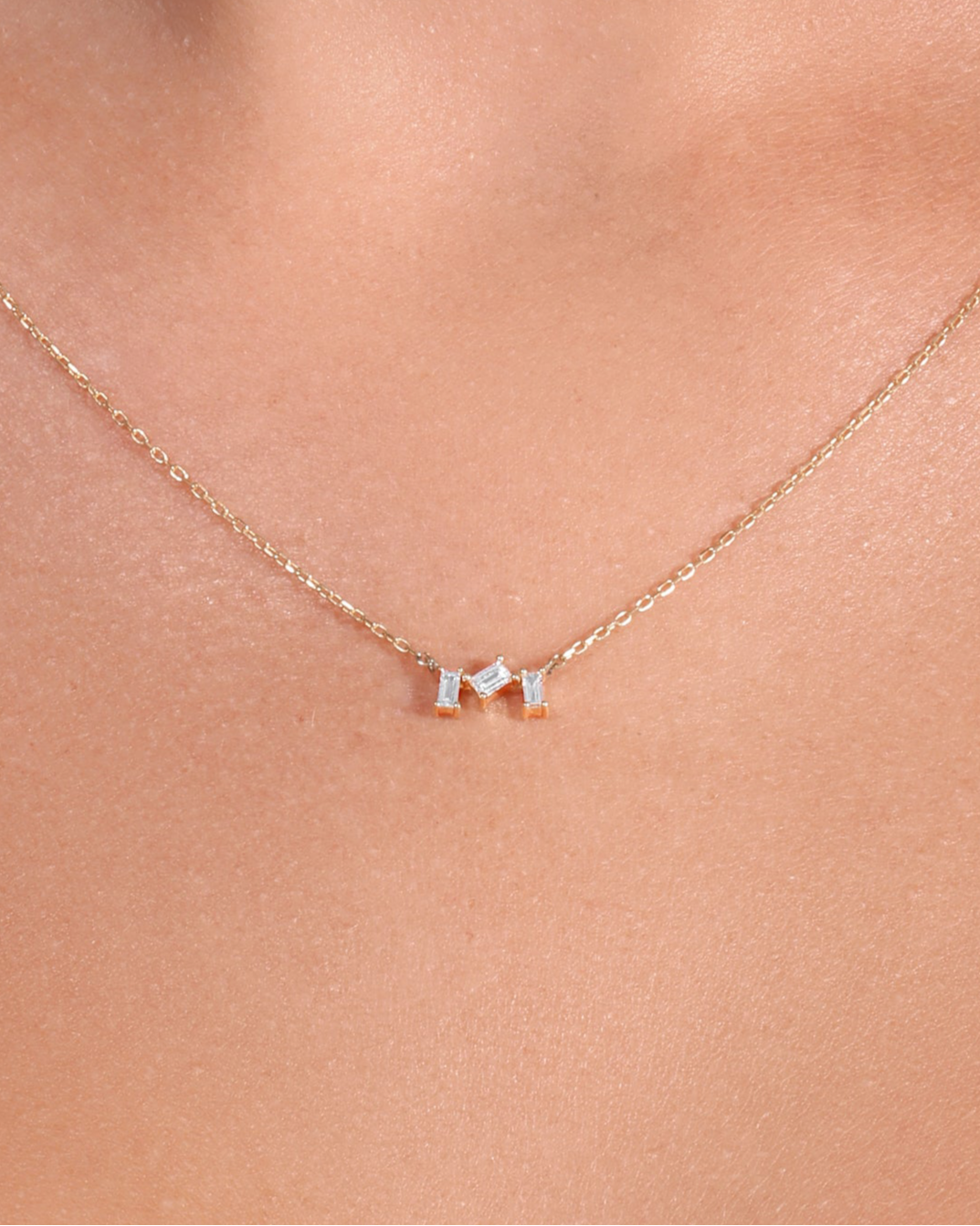 Necklace with small pendants on a person wearing a white top