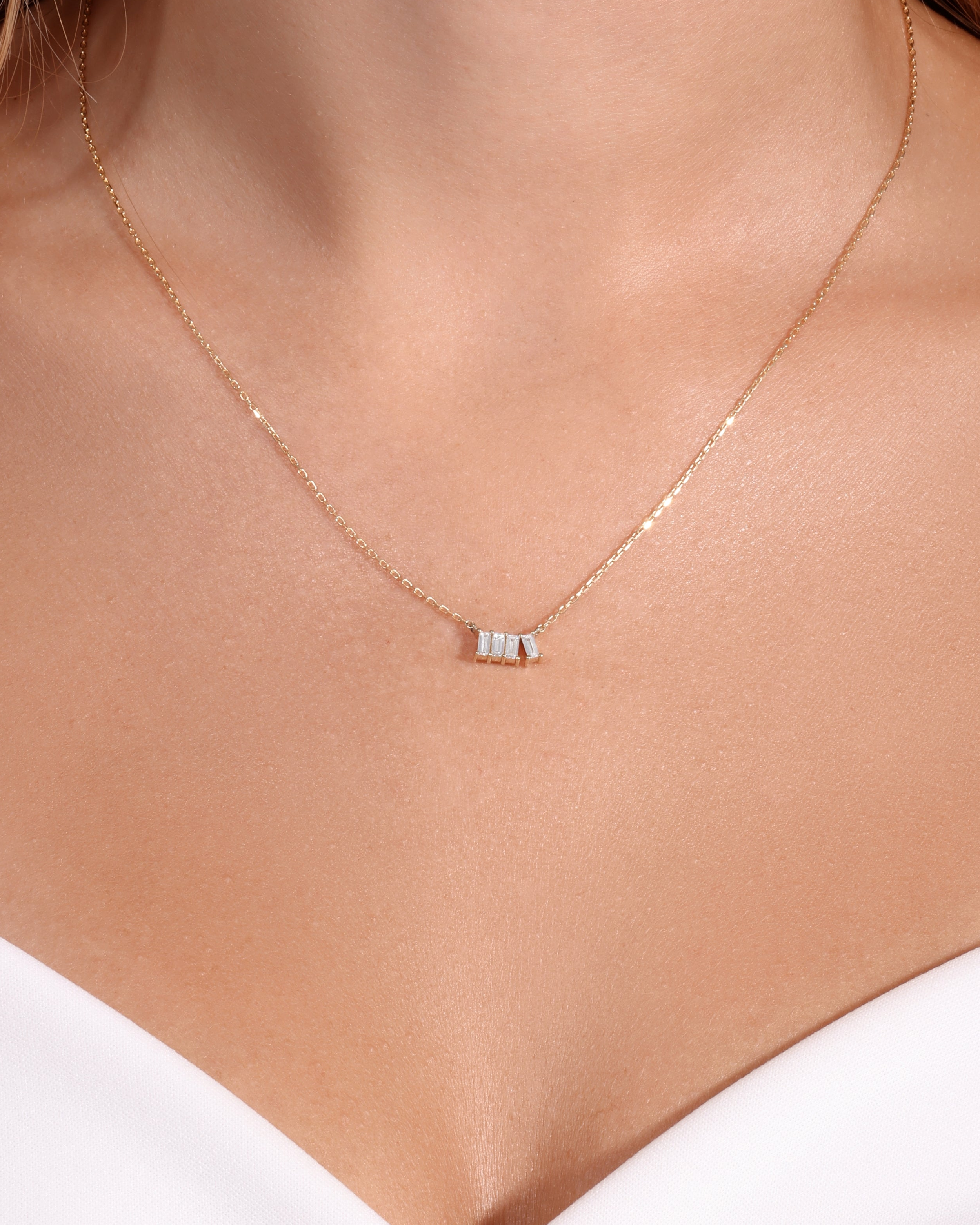 Necklace with a small pendant on a person wearing a white top