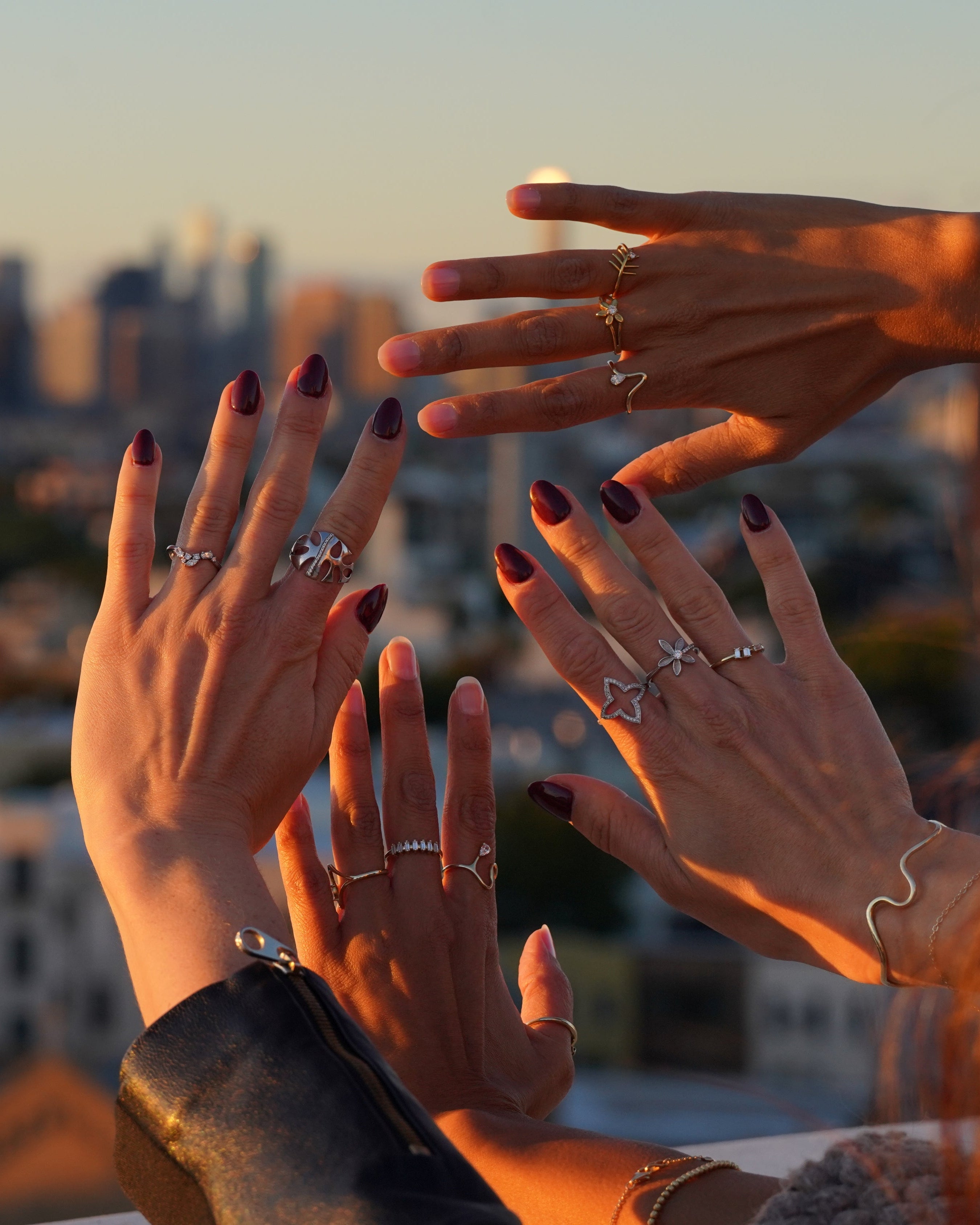 Hands with rings against a cityscape during sunset