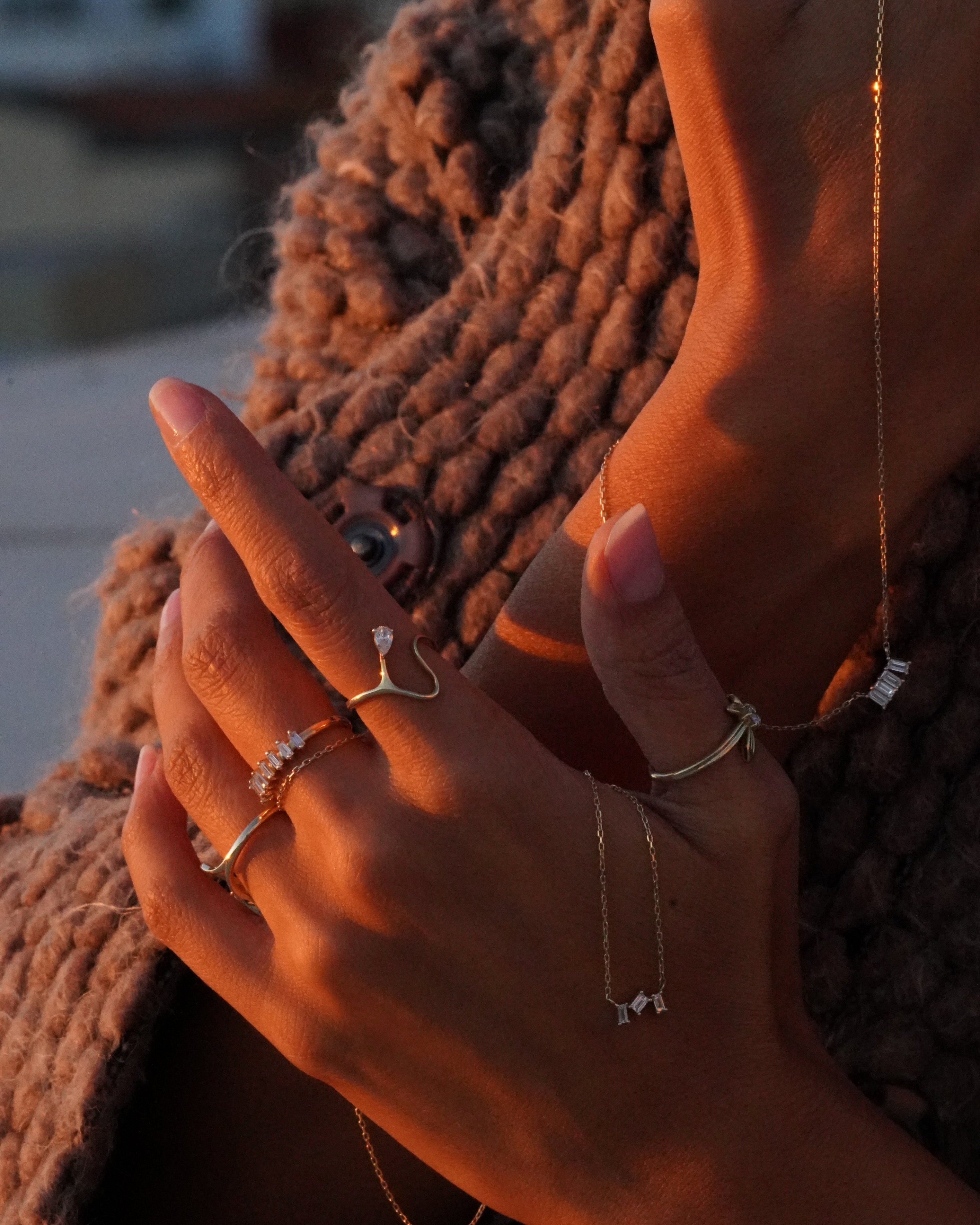 Close-up of hands with rings on a textured surface