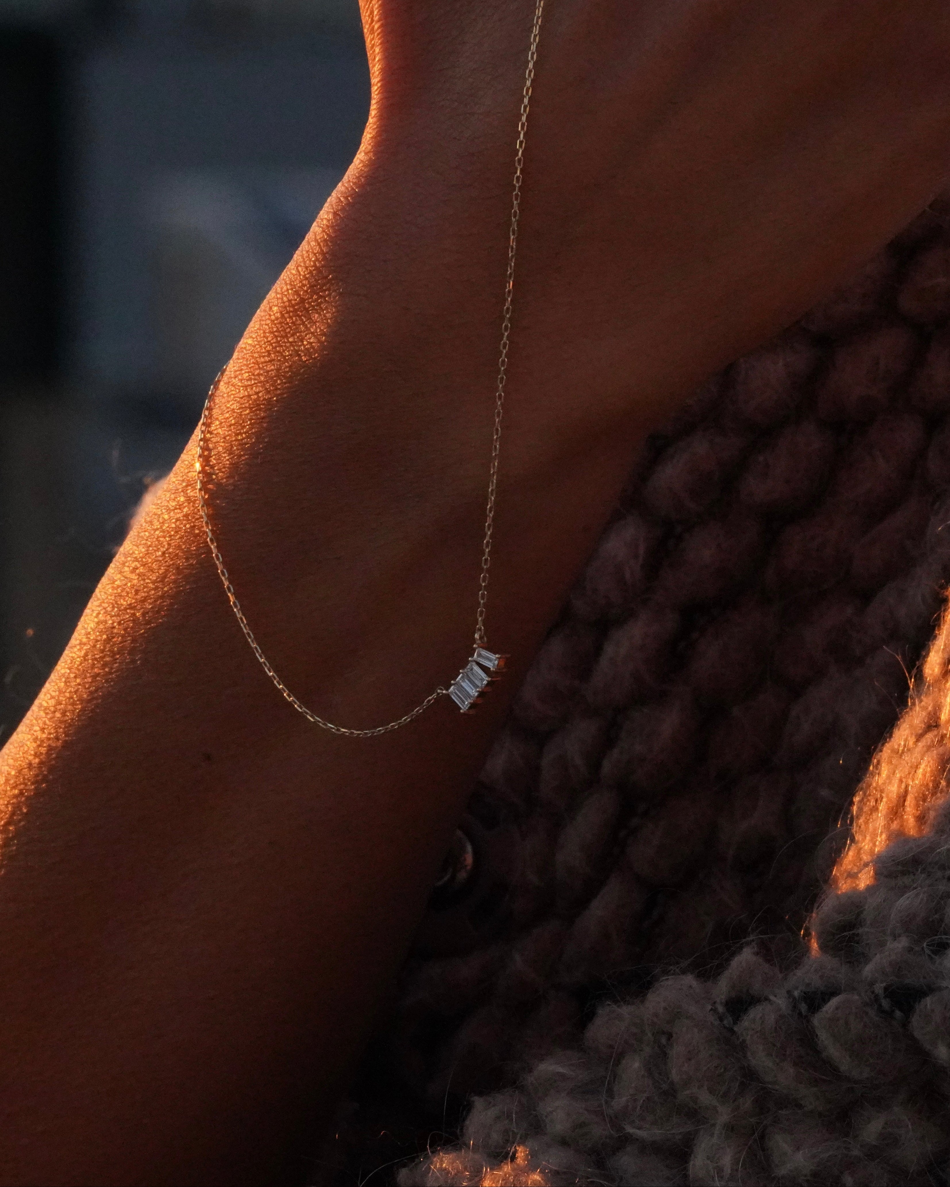 Close-up of a person with a delicate gold anklet on a textured surface.