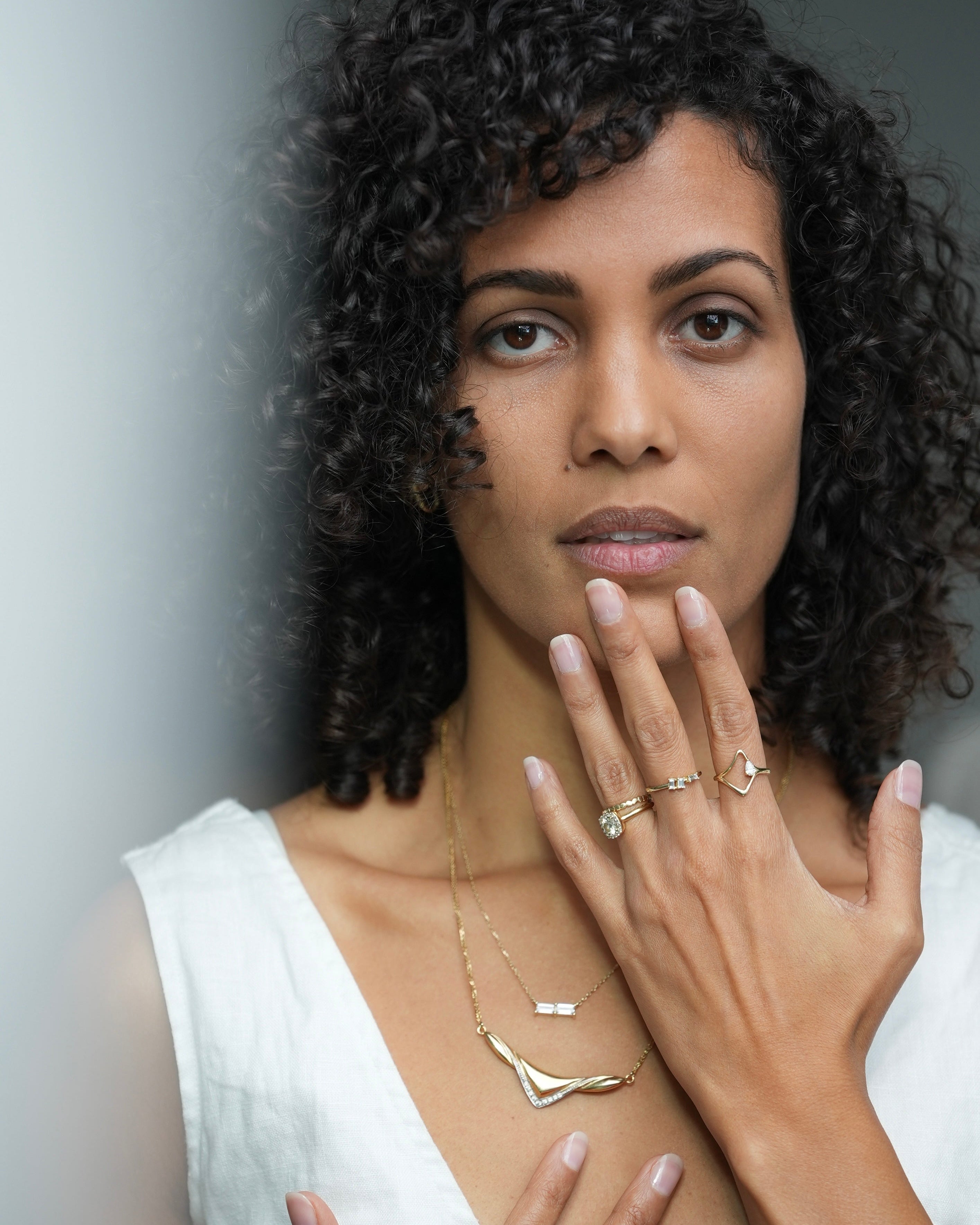 Woman wearing gold jewelry with a neutral background