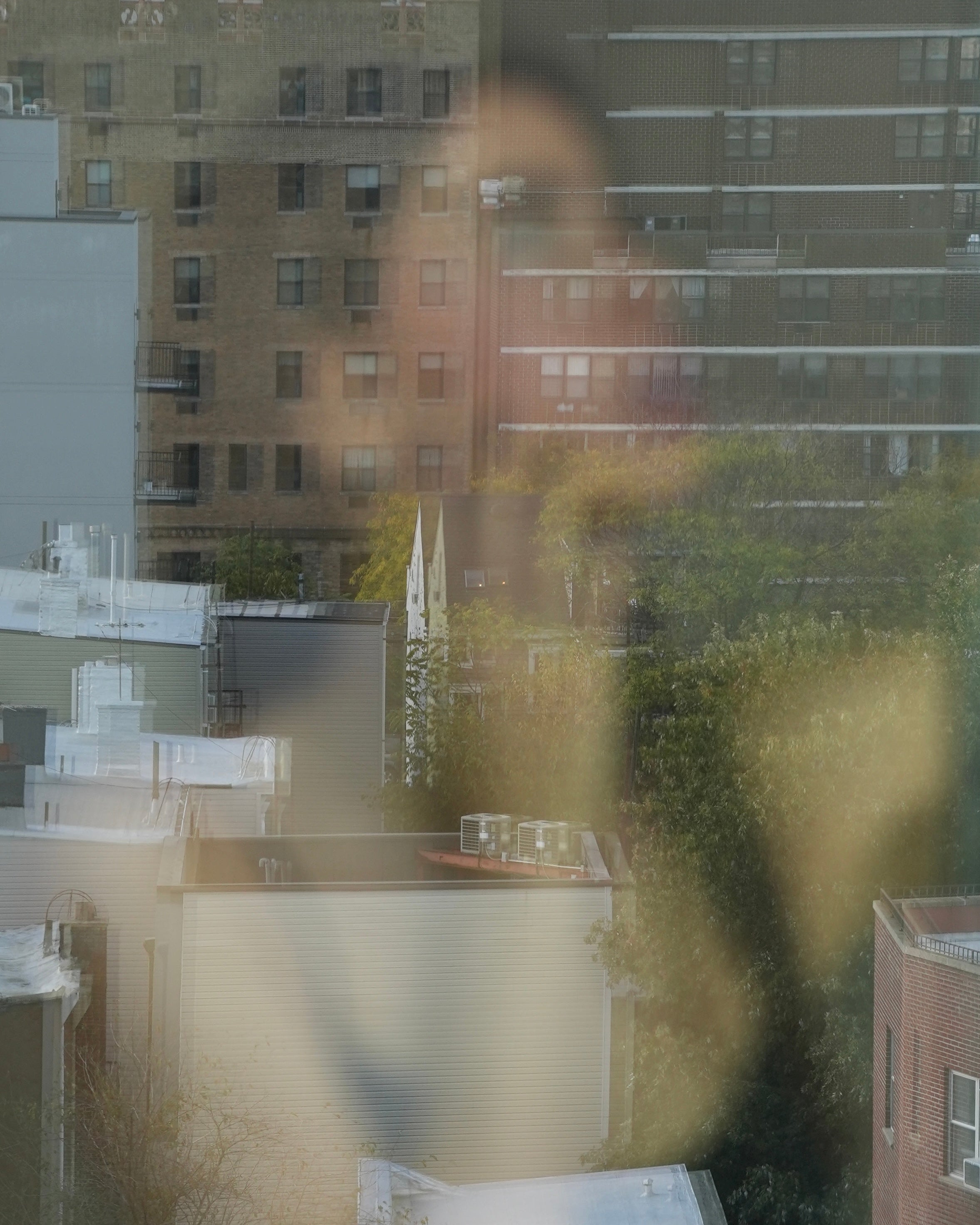 Person standing in front of a window with a blurred reflection of a cityscape.