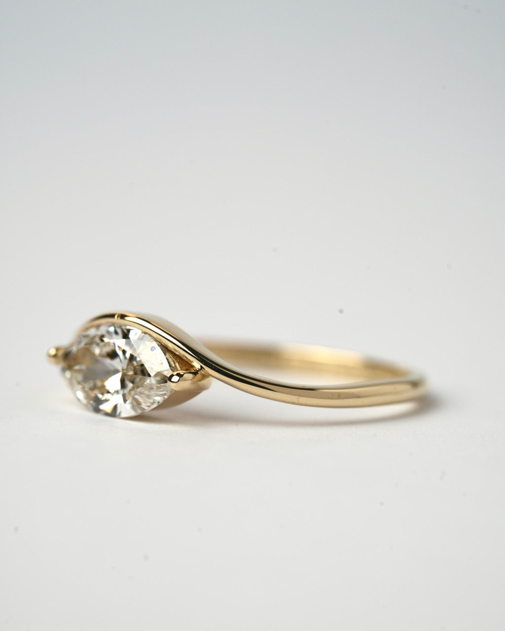Gold ring with a clear gemstone on a light gray background
