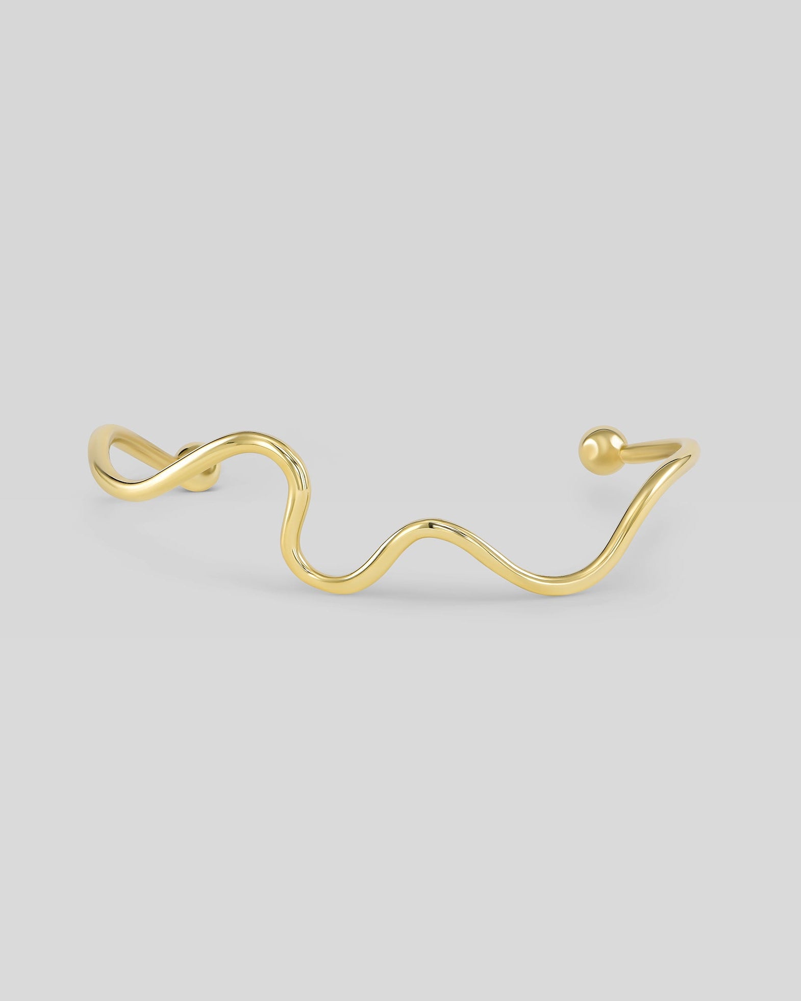 Gold ear cuff on a light gray background