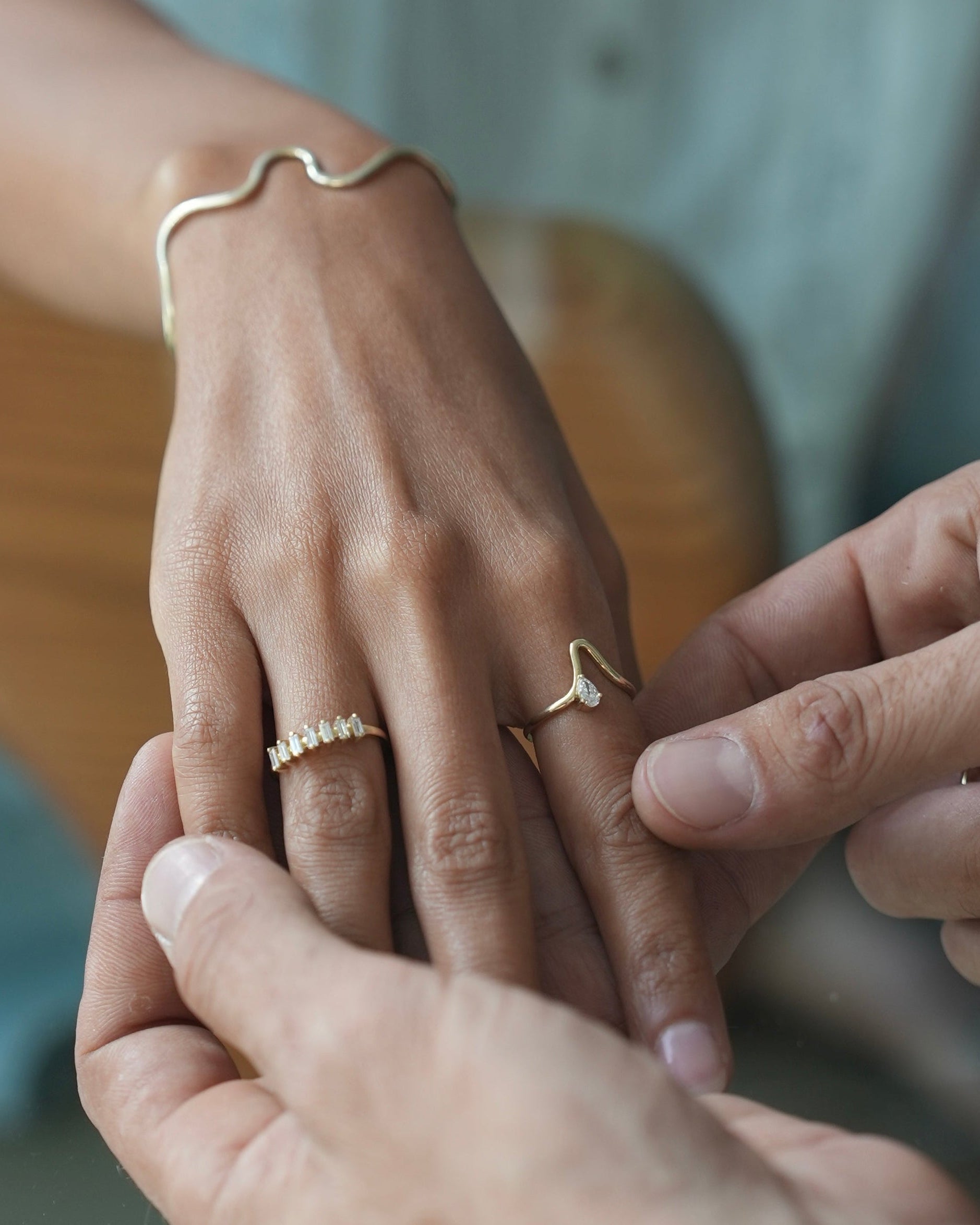 Two people holding hands with gold rings on a blurred background