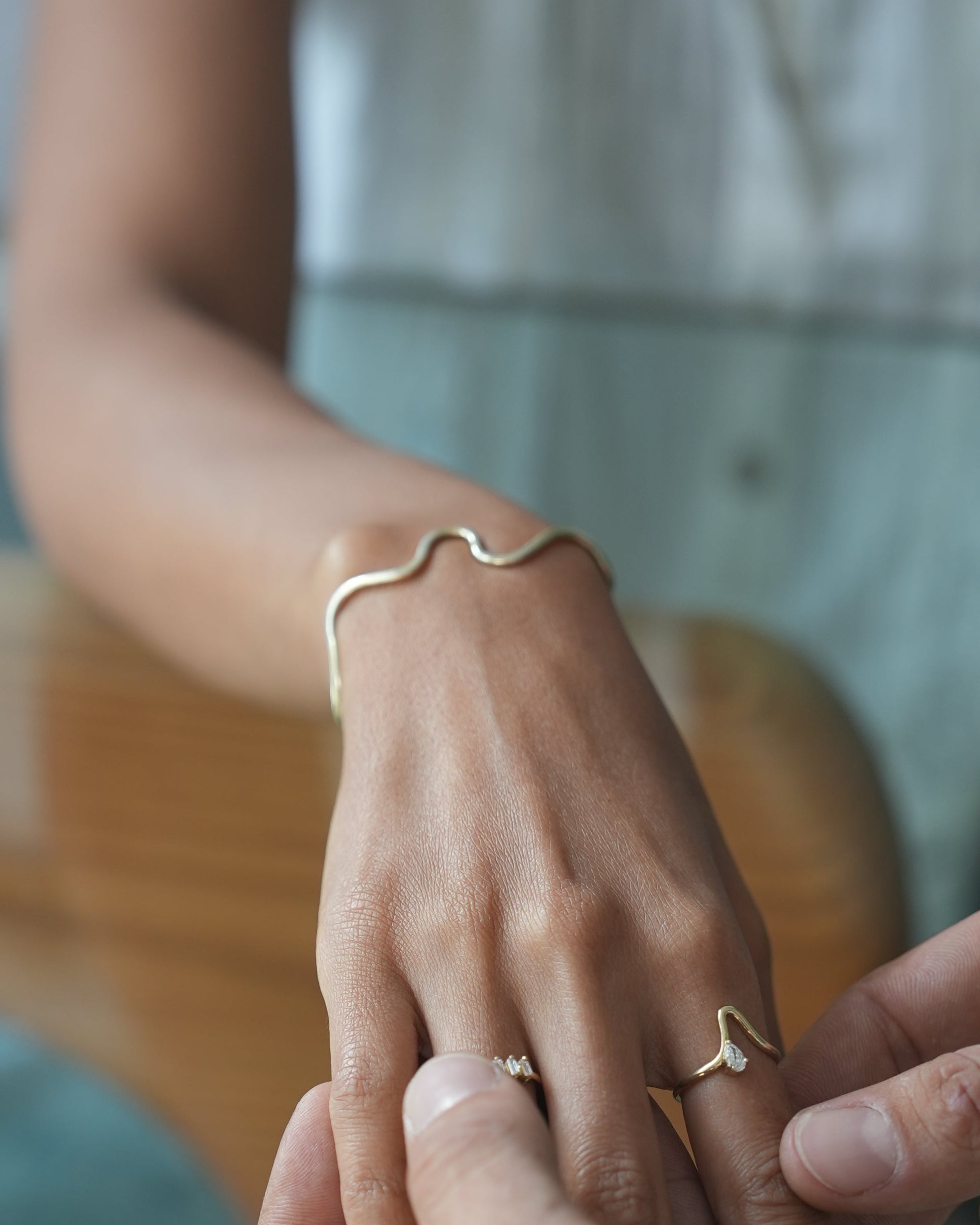 Two people holding hands with gold rings on a blurred background