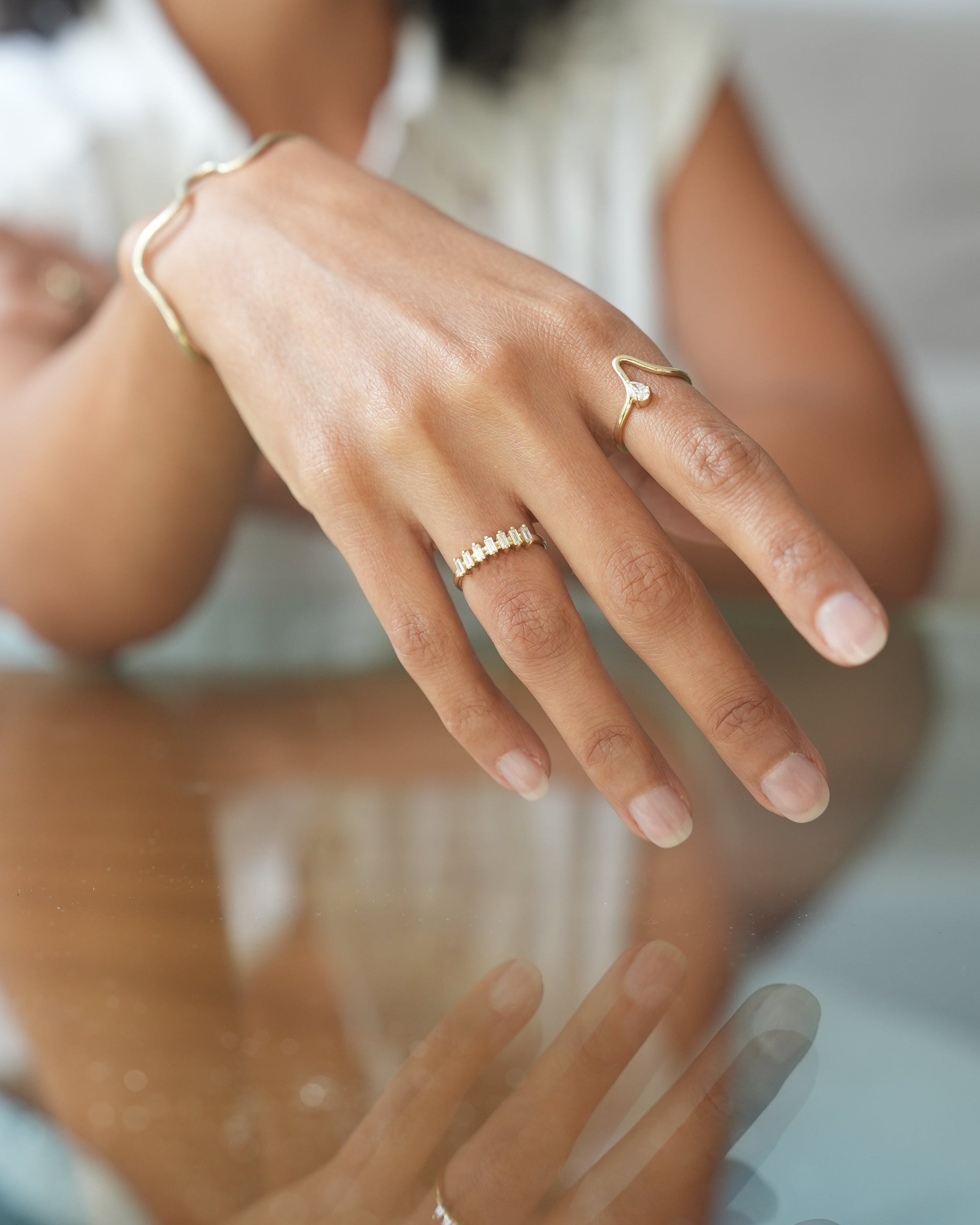Close-up of two people's hands with rings on a neutral background