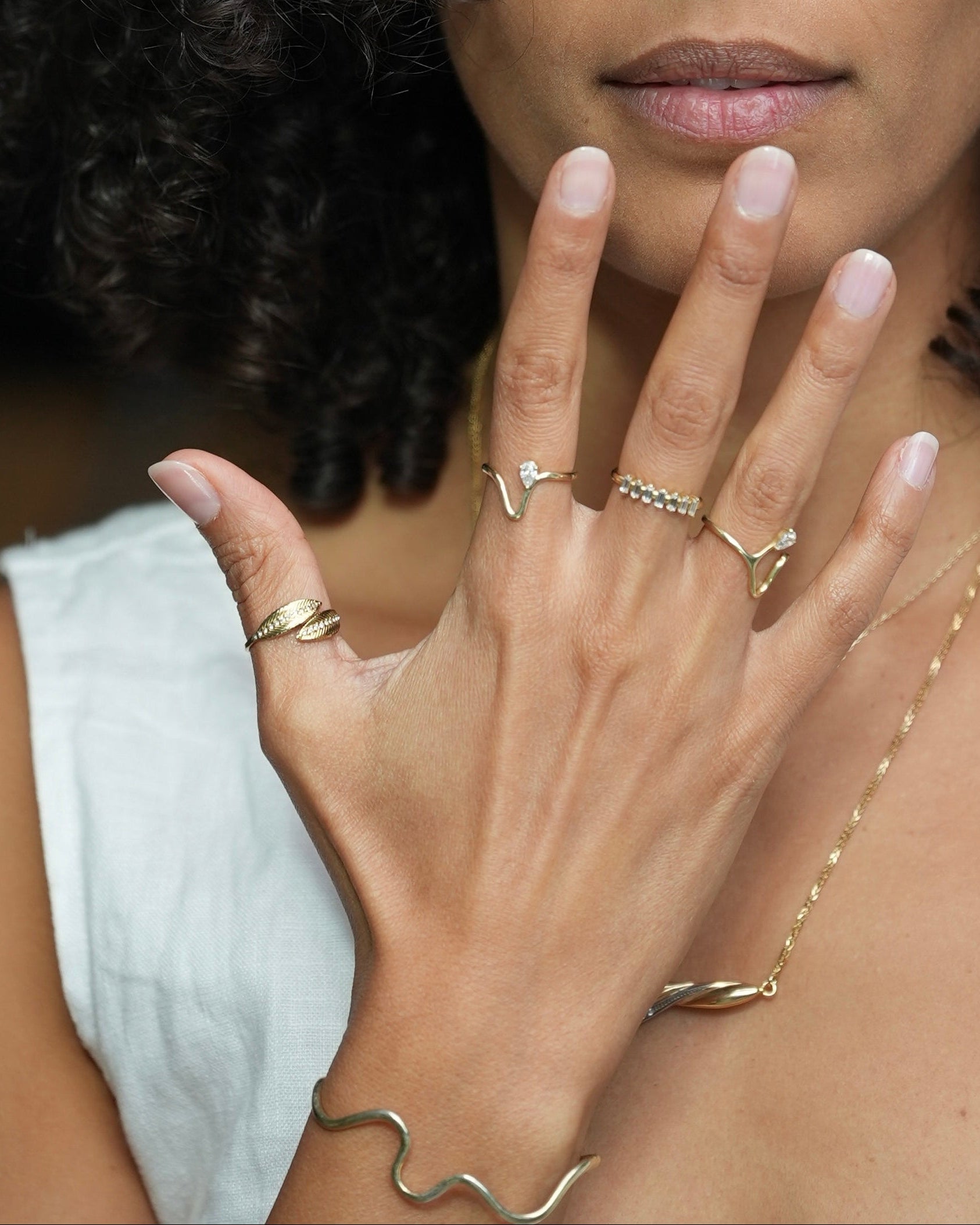 Close-up of a woman's hand wearing gold jewelry with a blurred background