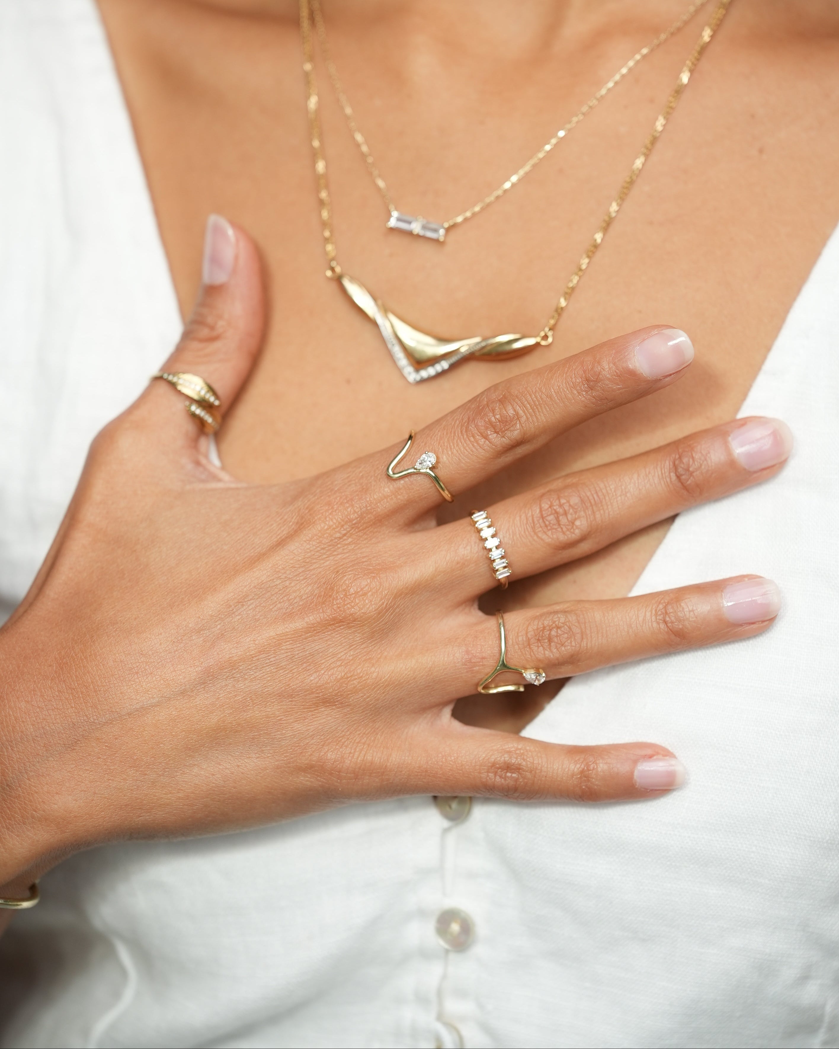 Close-up of a hand with multiple gold rings on a white background
