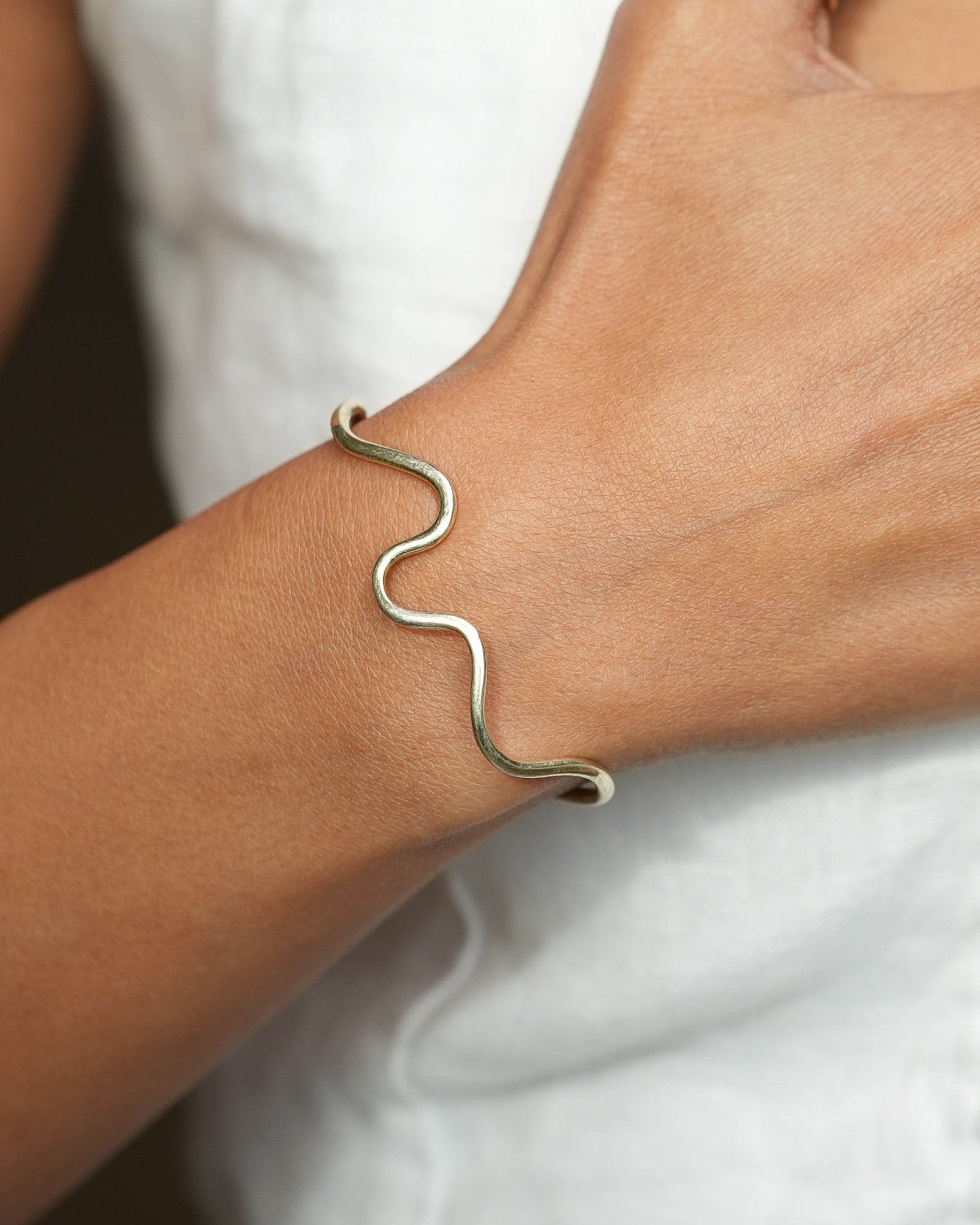 Close-up of a hand wearing gold jewelry on a white background