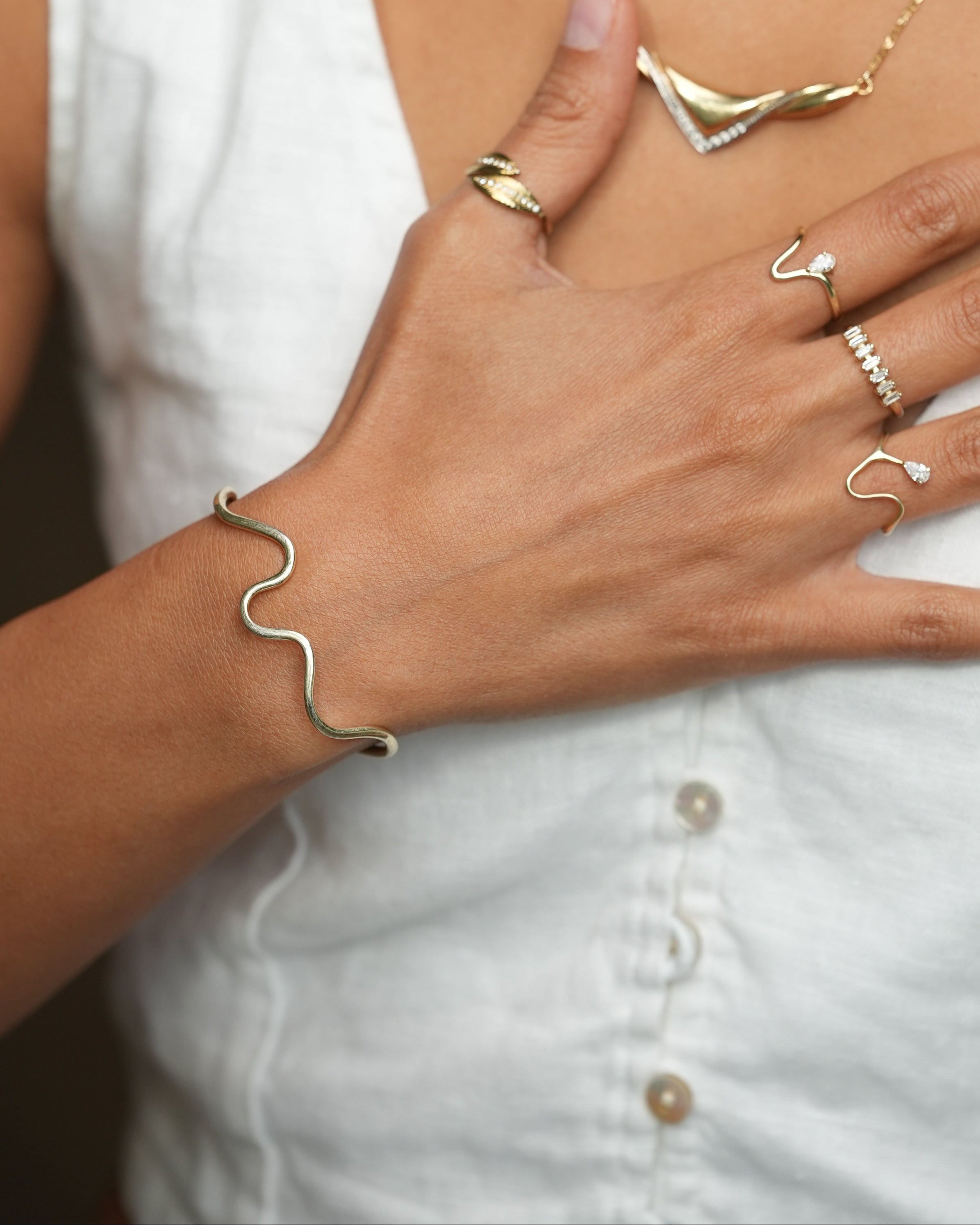 Hand wearing multiple gold rings with a blurred white background