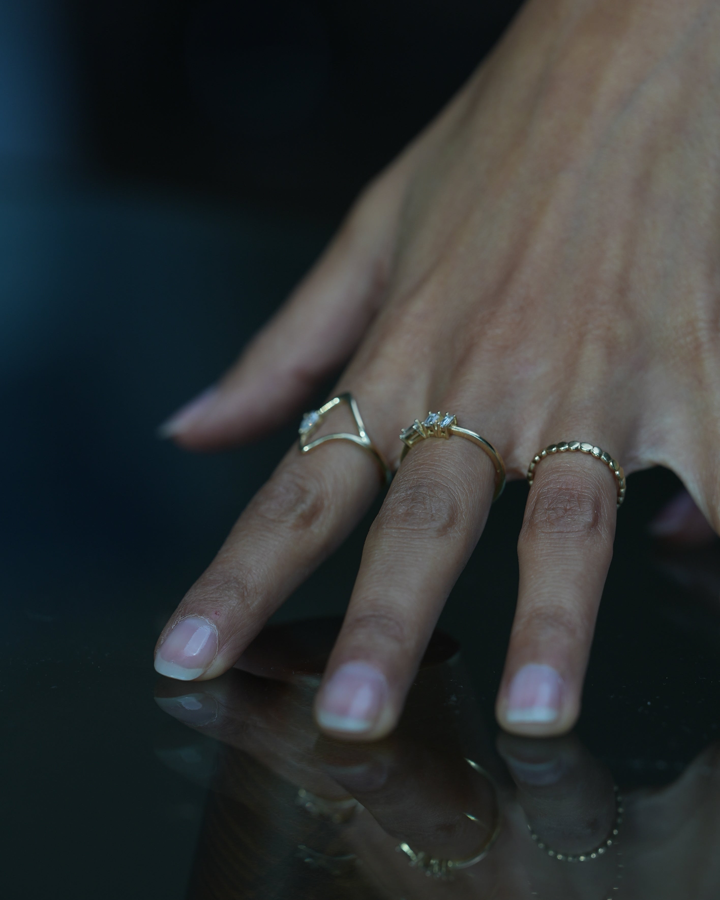 Close-up of a hand with multiple gold rings on a dark background