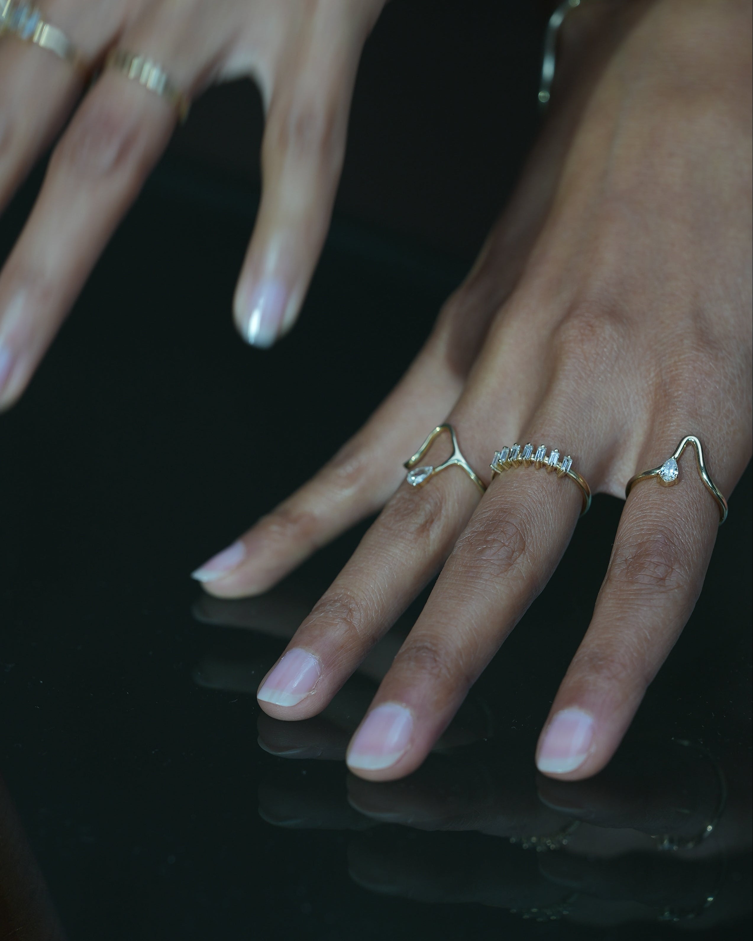 Close-up of hands with multiple rings on a dark background