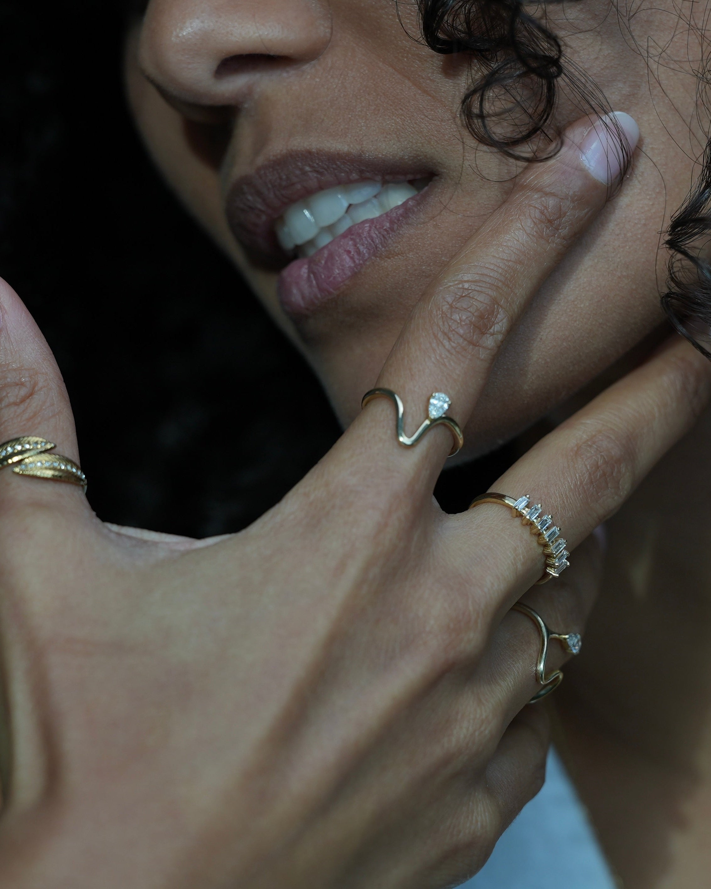 Close-up of a person's hand with multiple rings on a dark background