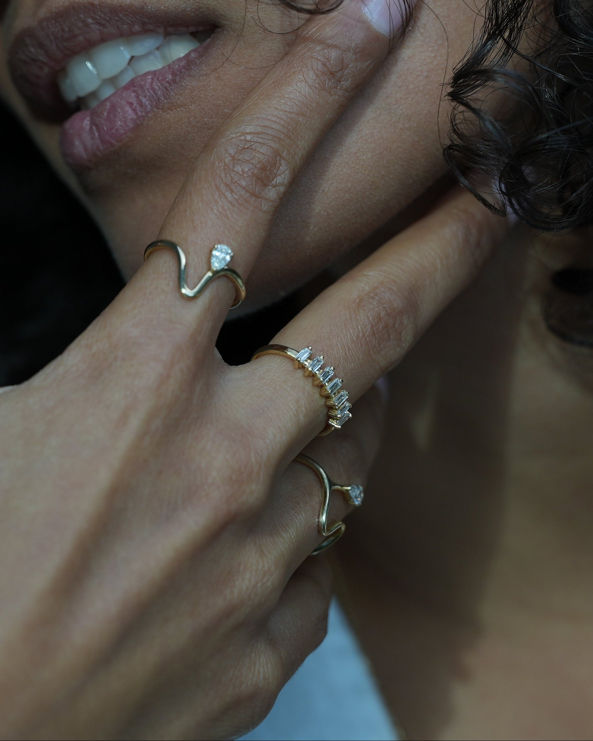 Close-up of a hand with multiple rings on a dark background