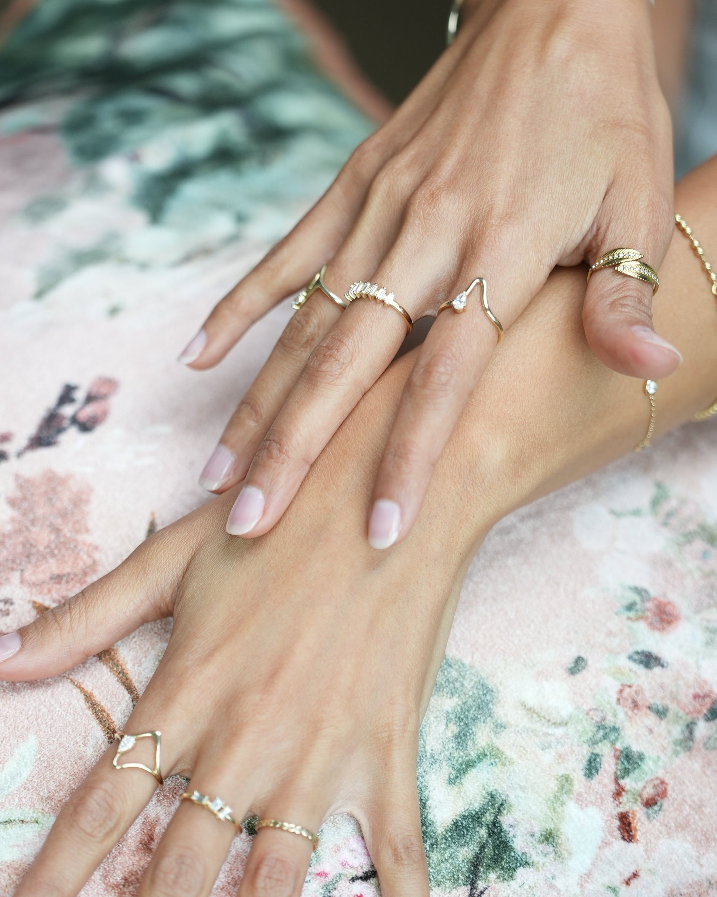 Close-up of hands with gold rings on a floral fabric background
