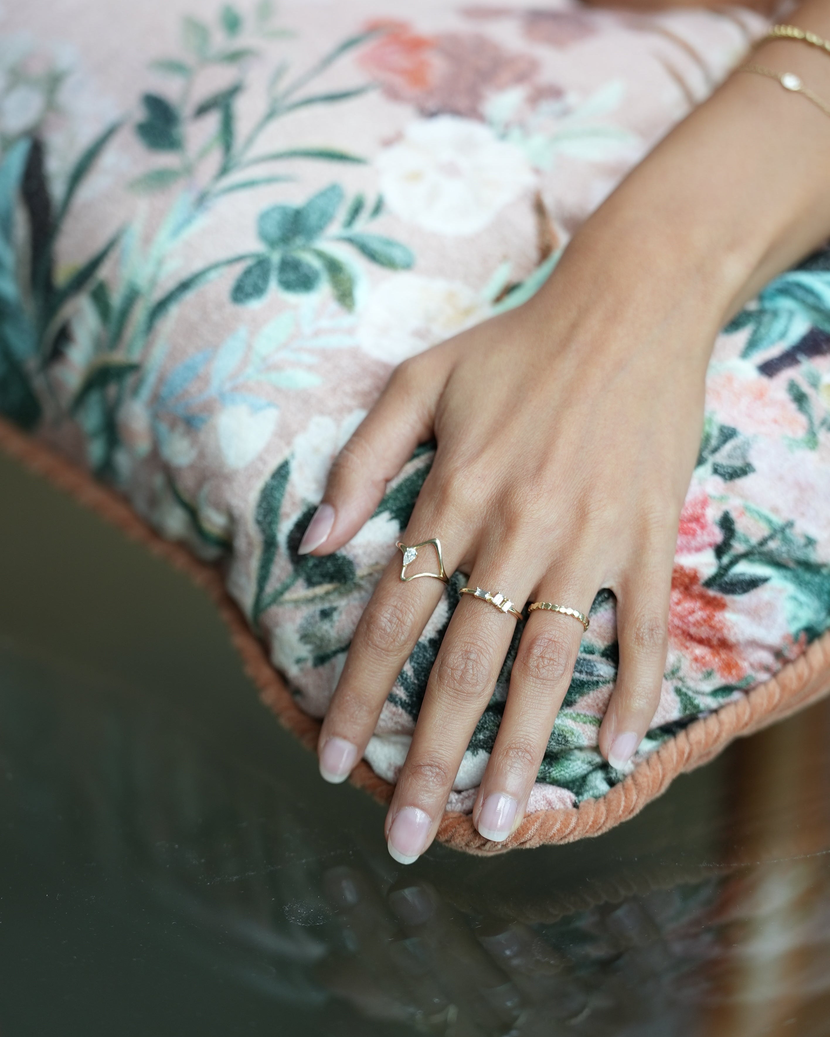 Close-up of a hand with rings on a floral cushion