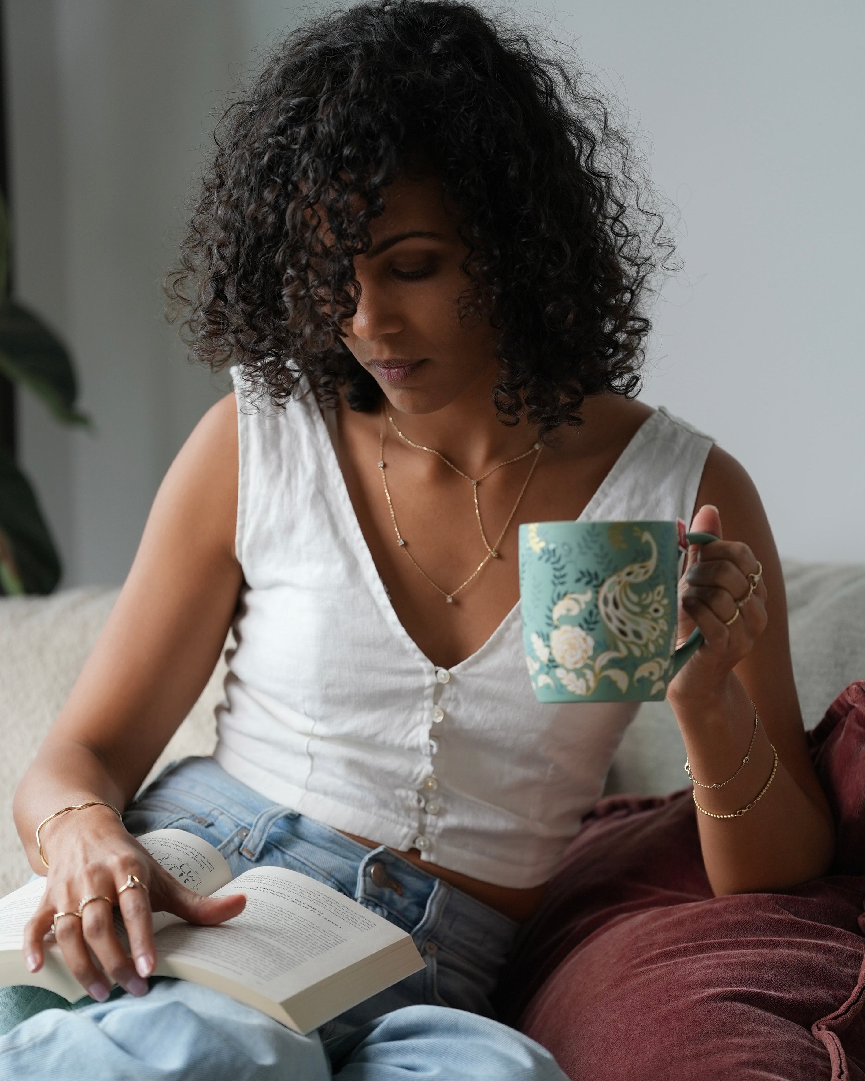 Woman reading a book and holding a mug on a couch