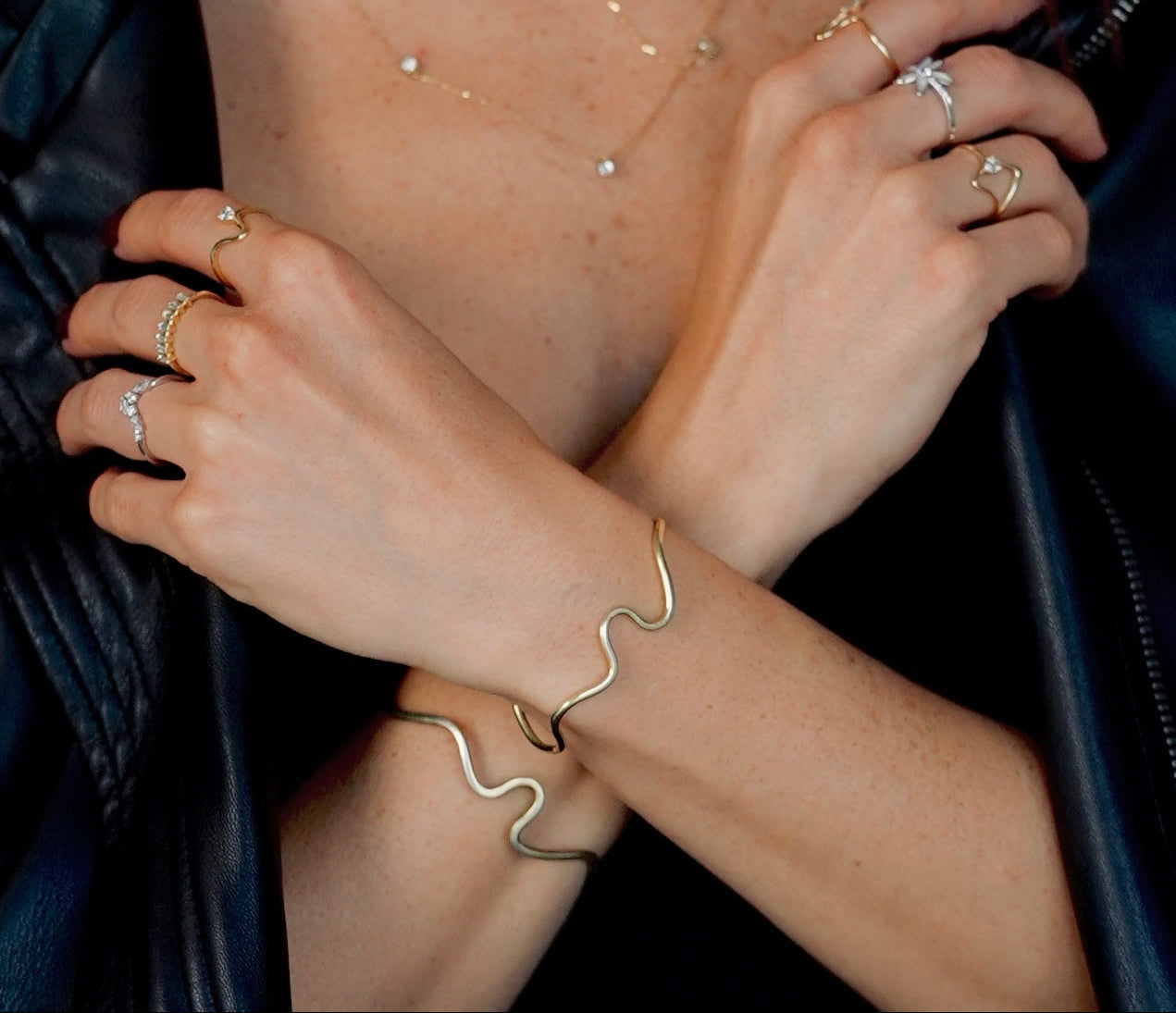 Close-up of hands wearing multiple rings on a dark background