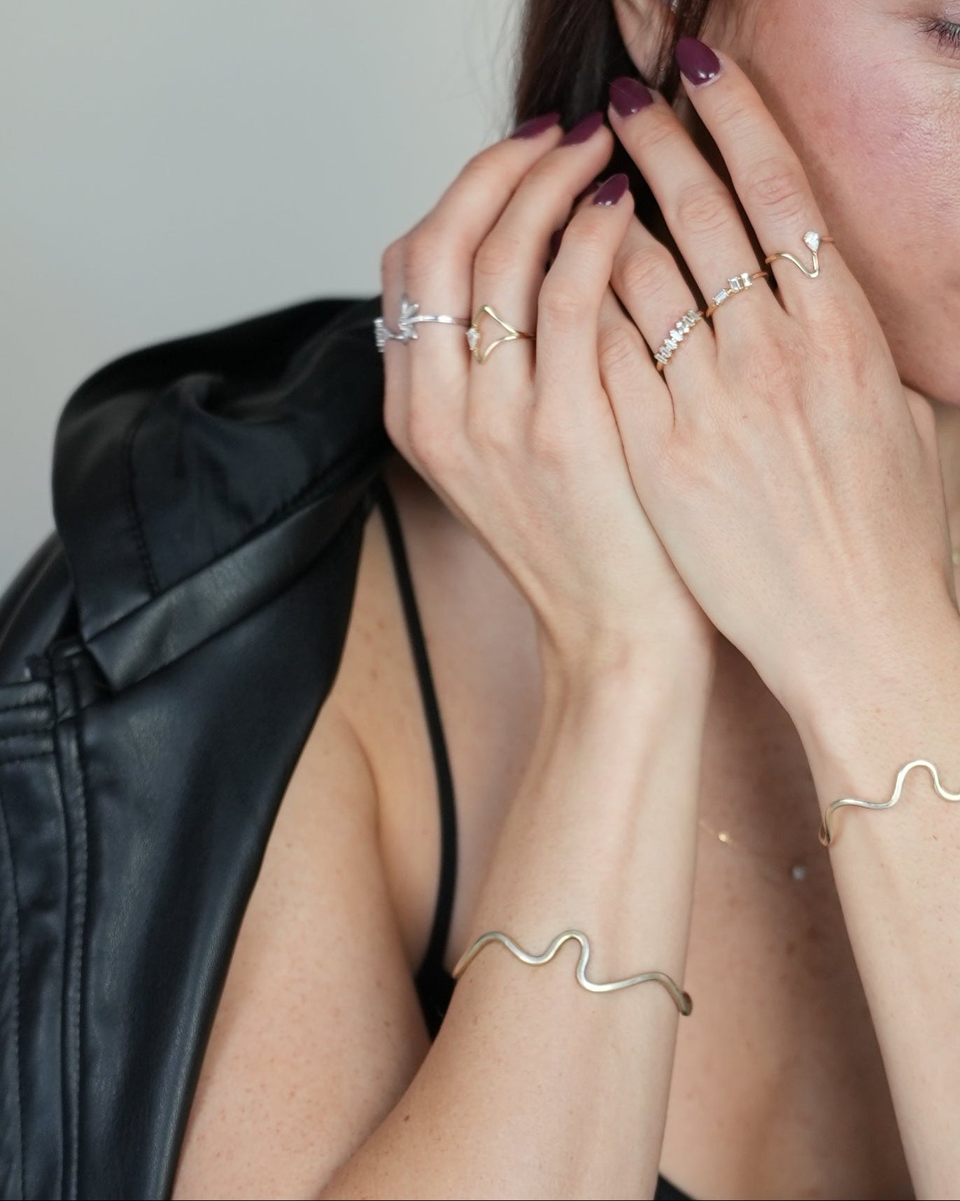 Woman in a black dress sitting on a white floor with a neutral expression.