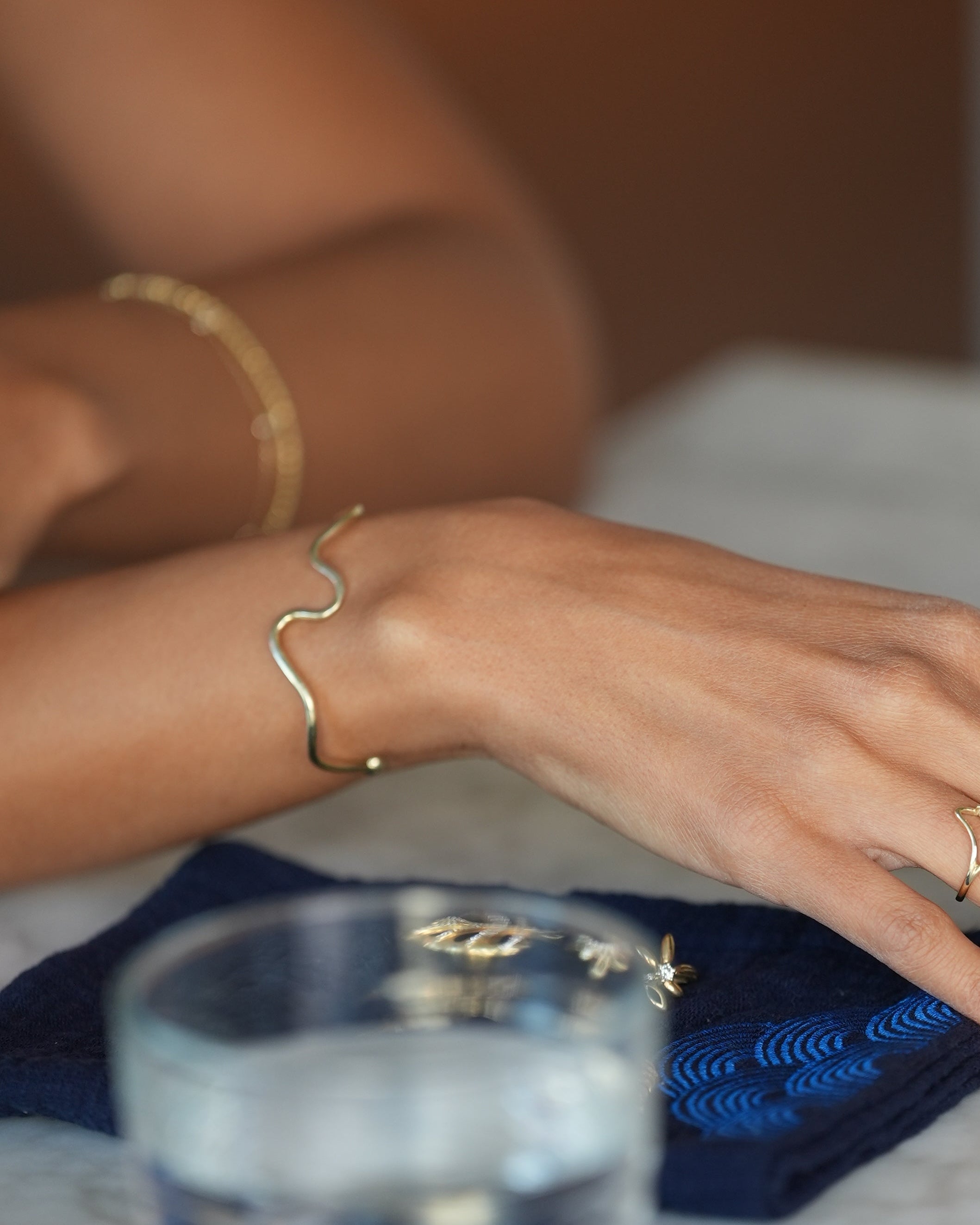 Hand wearing gold jewelry with a blurred background