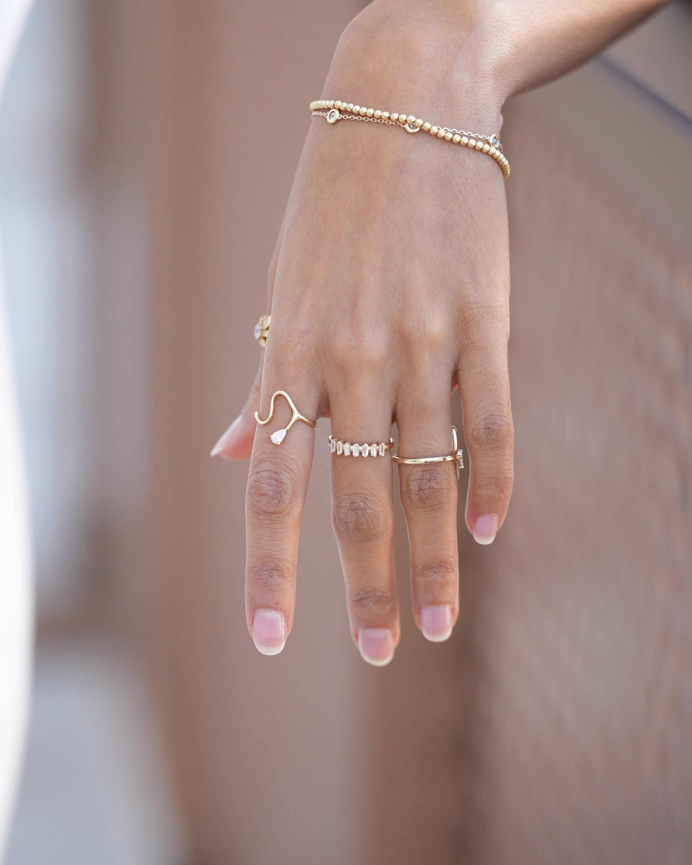 Hand with multiple gold rings on a blurred background