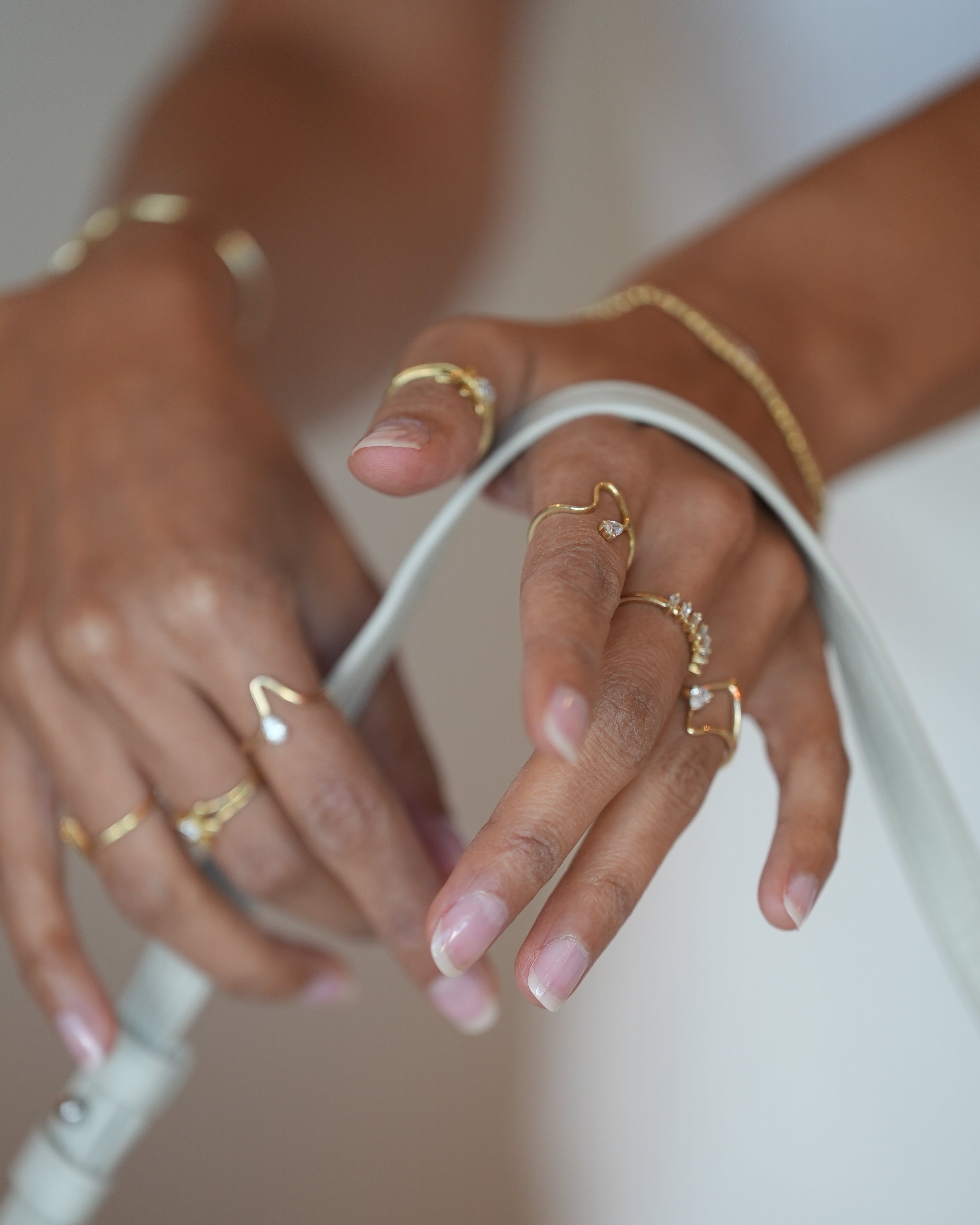 Close-up of hands with gold rings and bracelets on a white background