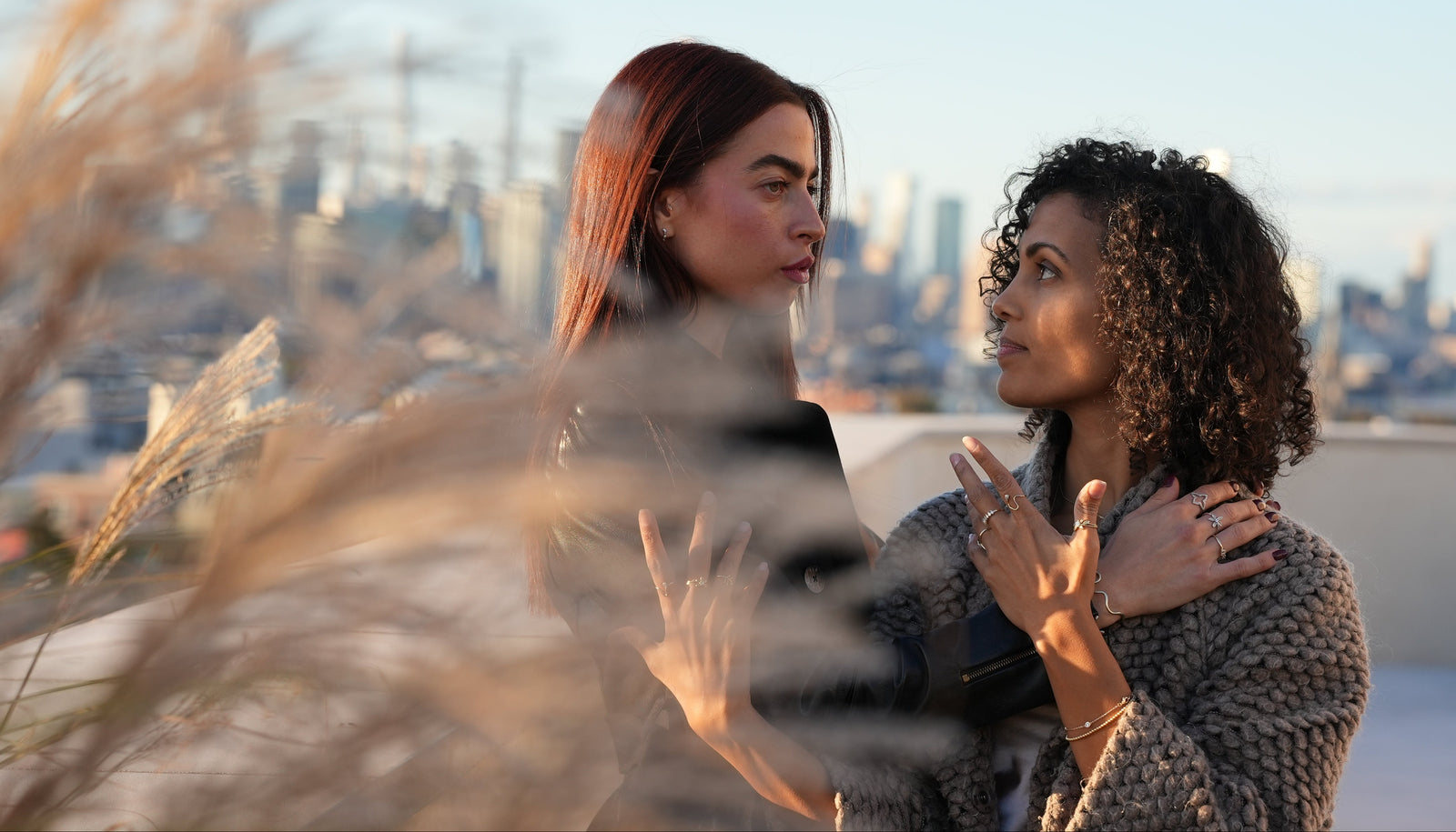 Two women embracing on a rooftop with a cityscape in the background