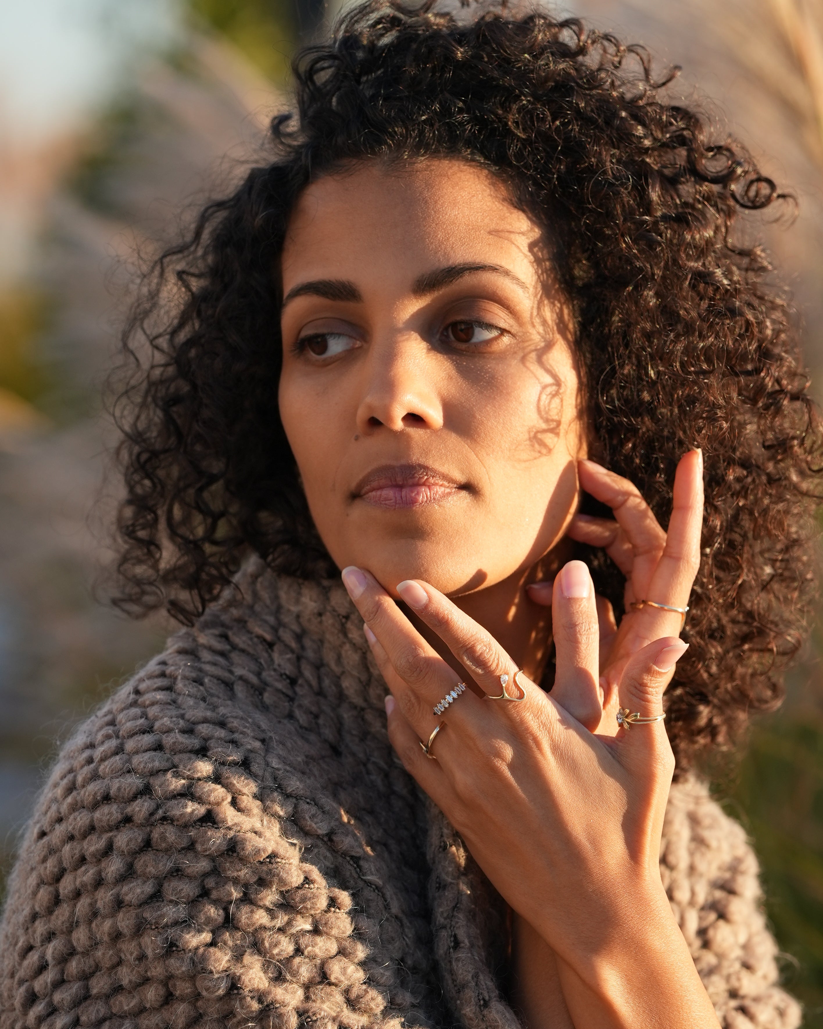 Woman with curly hair and a textured sweater in a natural setting
