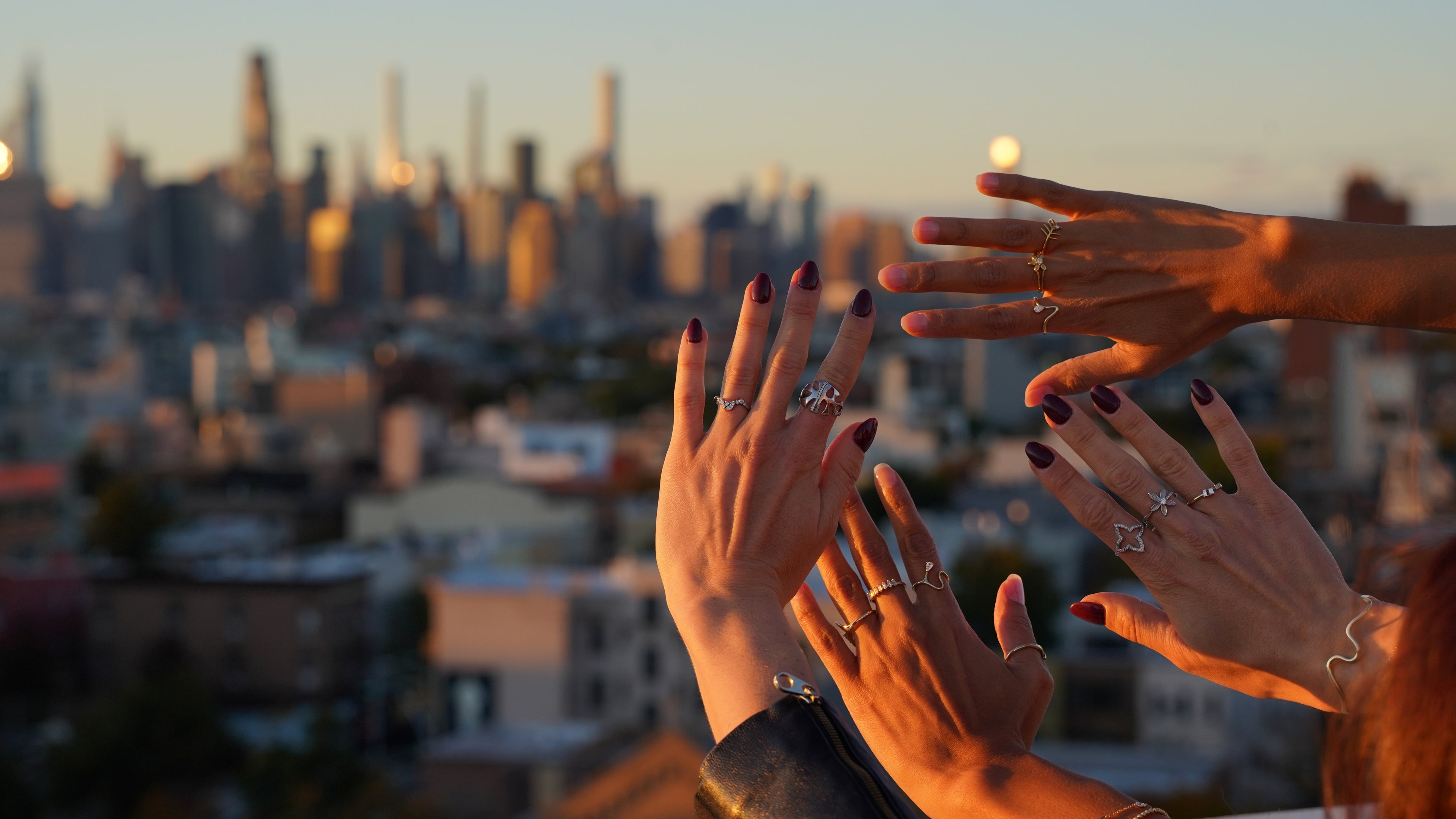 Hands with rings against a cityscape at sunset