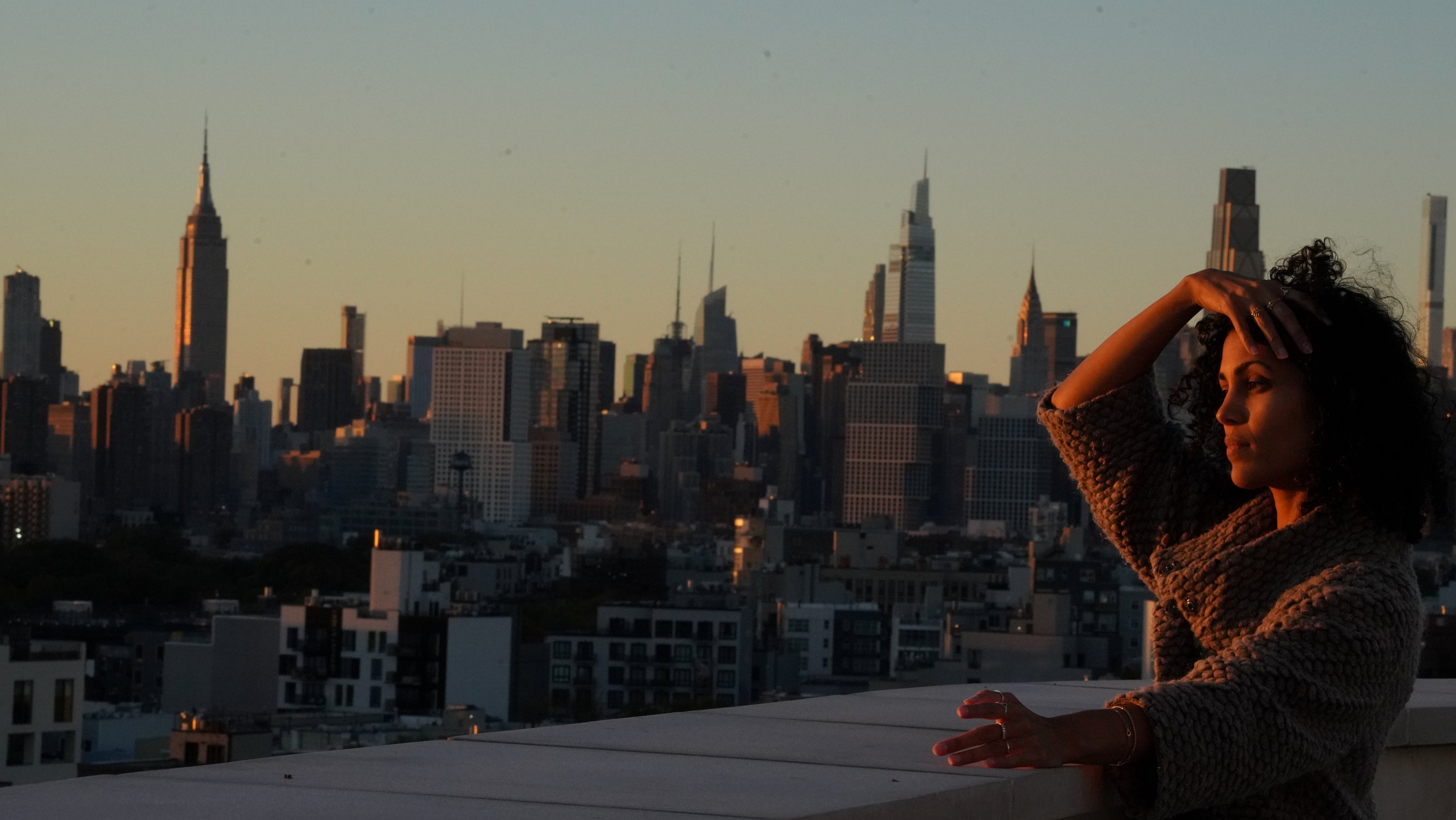 Person on a rooftop with a city skyline at sunset