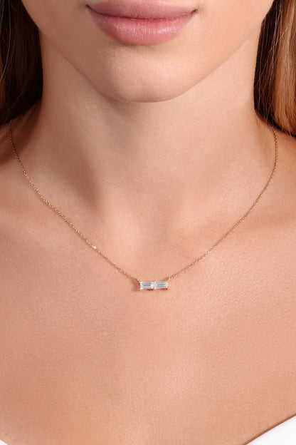Necklace with a small pendant worn by a person in a white top