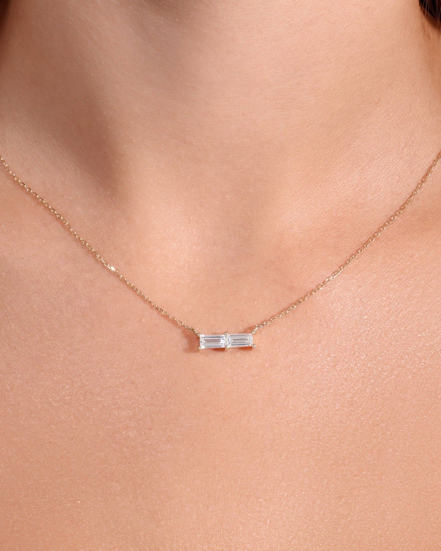 Necklace with a small pendant worn by a person in a white top