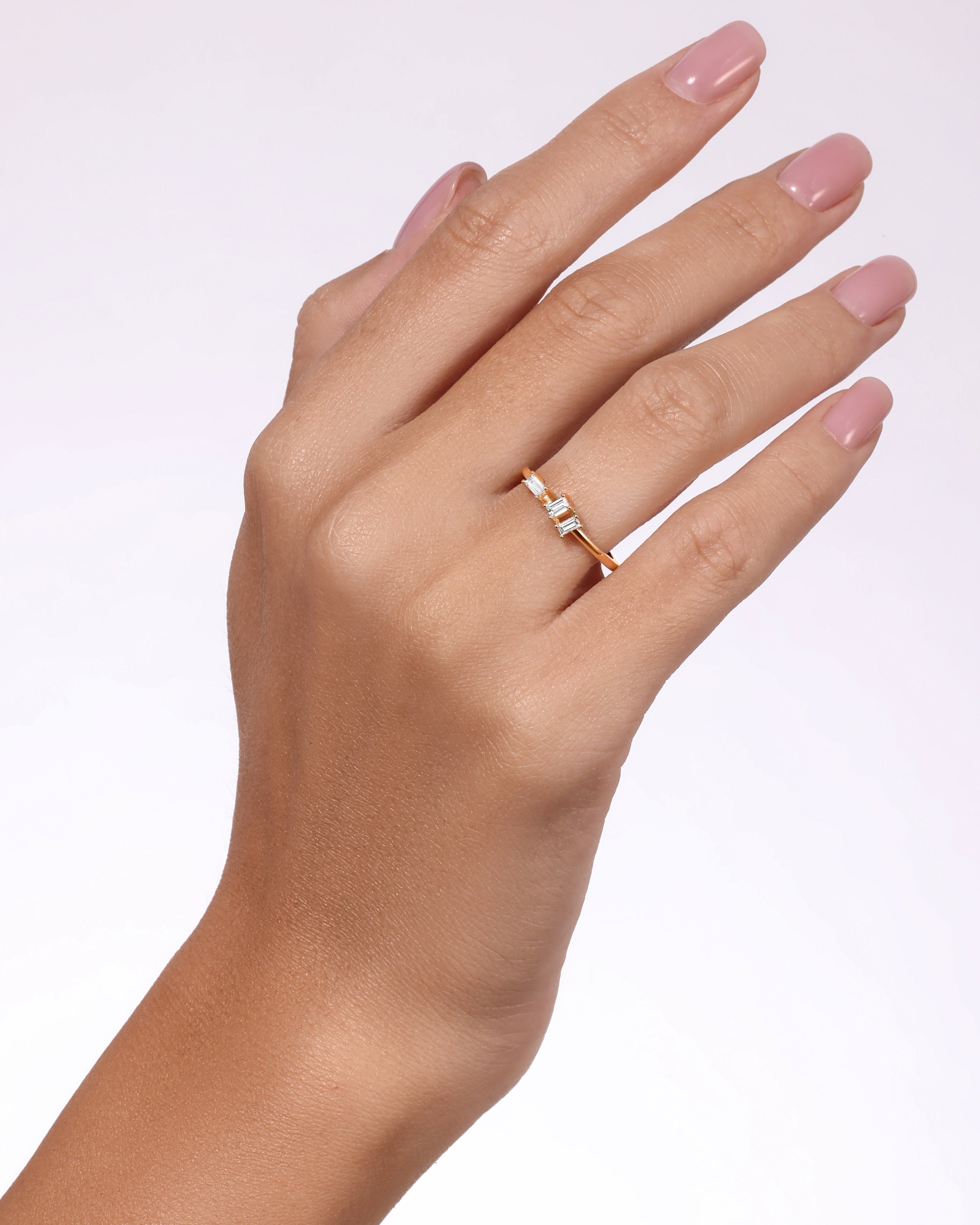 Hand wearing a gold ring on a white background