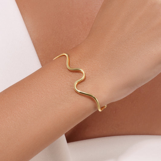 Gold bracelet on a wrist with a neutral background