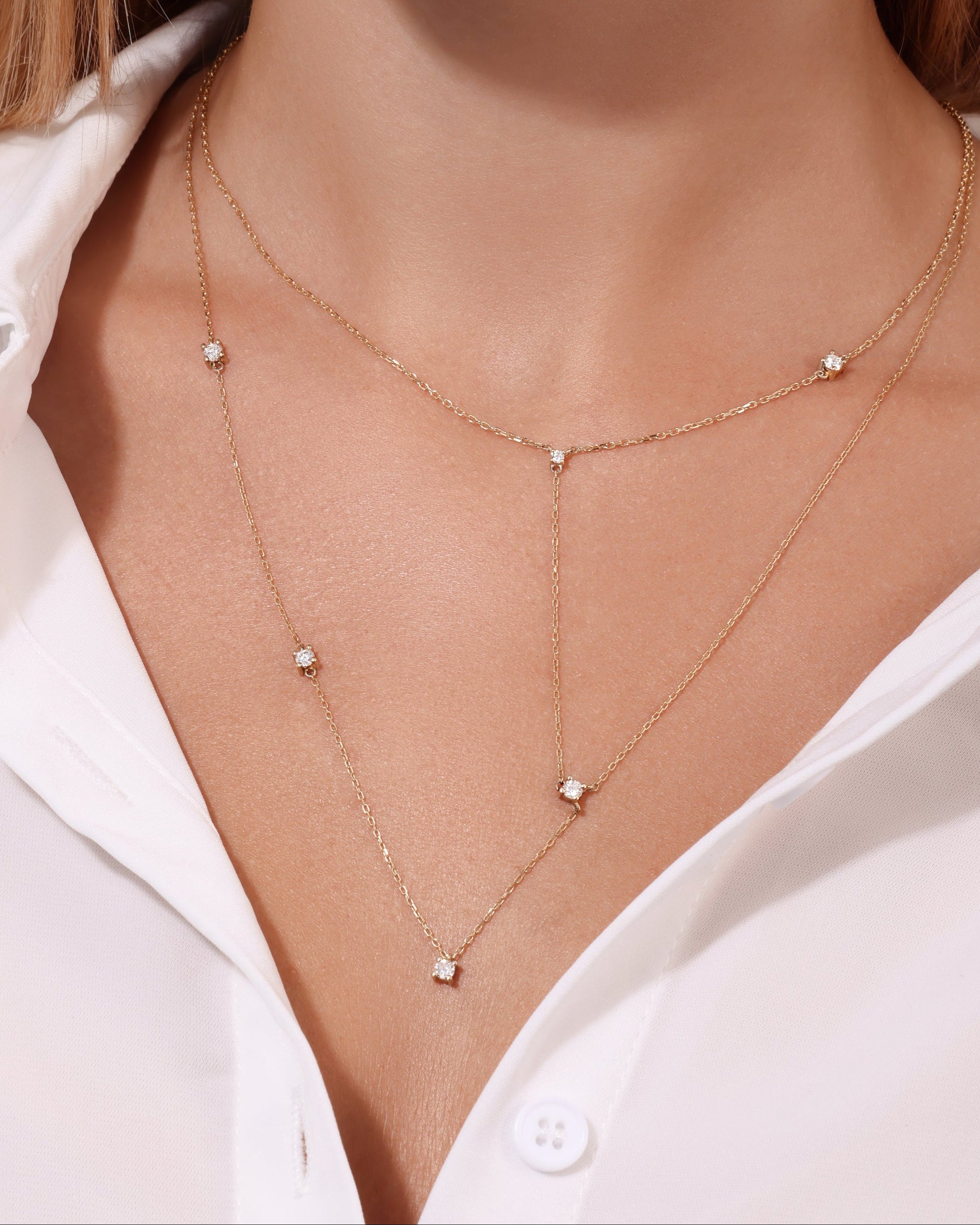 Close-up of a person wearing a delicate gold necklace with small diamonds