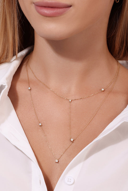 Close-up of a person wearing a delicate gold necklace with small diamonds