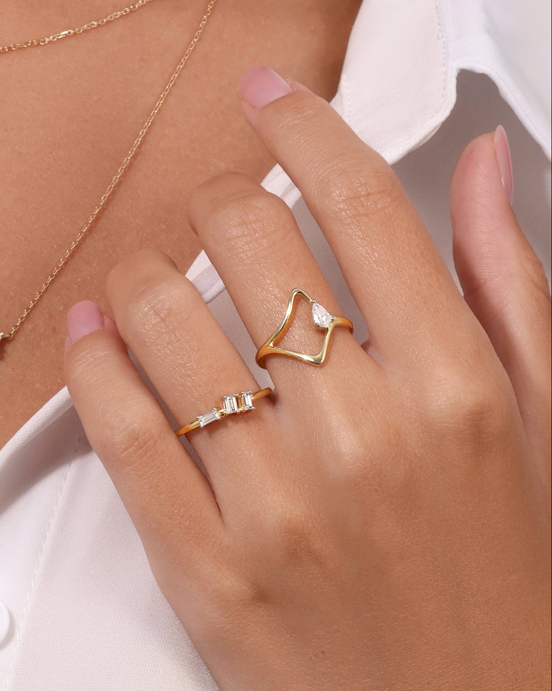Woman wearing gold necklaces and rings on a white background