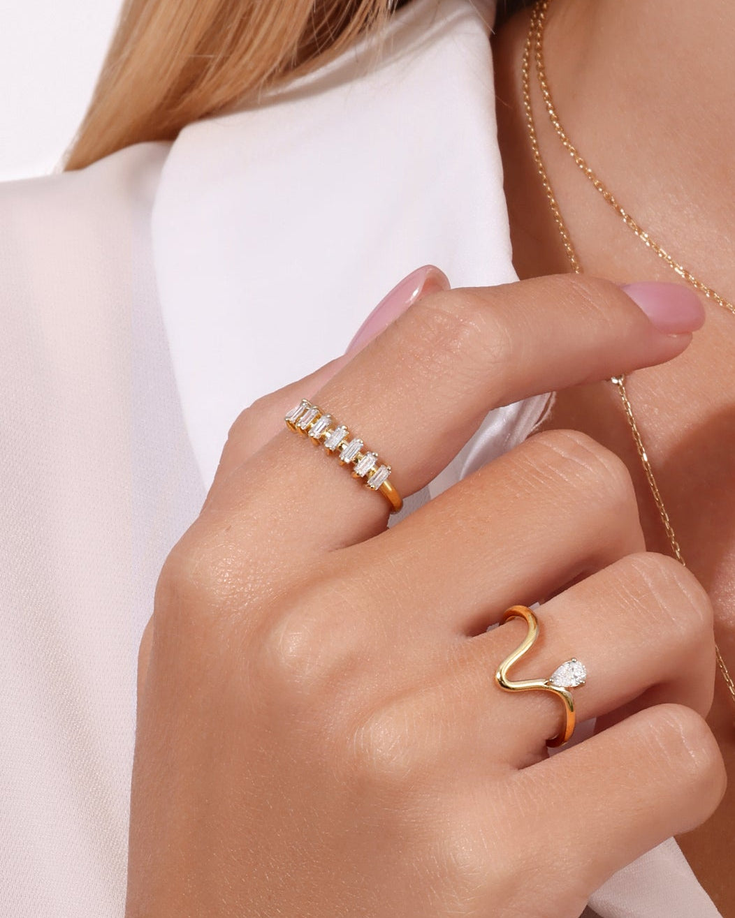 Woman wearing gold necklaces and rings on a white background